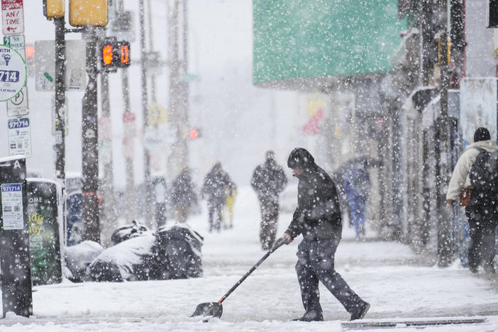 A person clears off a sidewalk during a winter snow storm in Philadelphia on Tuesday.