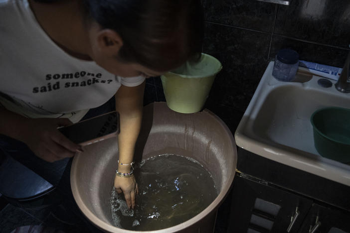 Sandra Martínez Martínez shows the dirty tap water she and her family are using as toilet water at her home in the municipality of Ecatepec, in the State of Mexico, on Sunday.