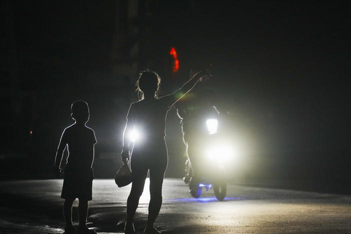 A woman and a boy attempt to hitch a ride during a scheduled power outage in Bauta, Cuba, Monday. The island is facing an energy crisis, with waves of blackouts worsening in recent weeks.