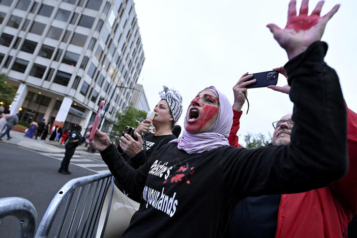 A demonstrator with red paint on their hand and face is seen behind a police barricade during a pro-Palestinian protest over the Israel-Hamas war at the White House Correspondents' Association Dinner, Saturday April 27, 2024, in Washington.