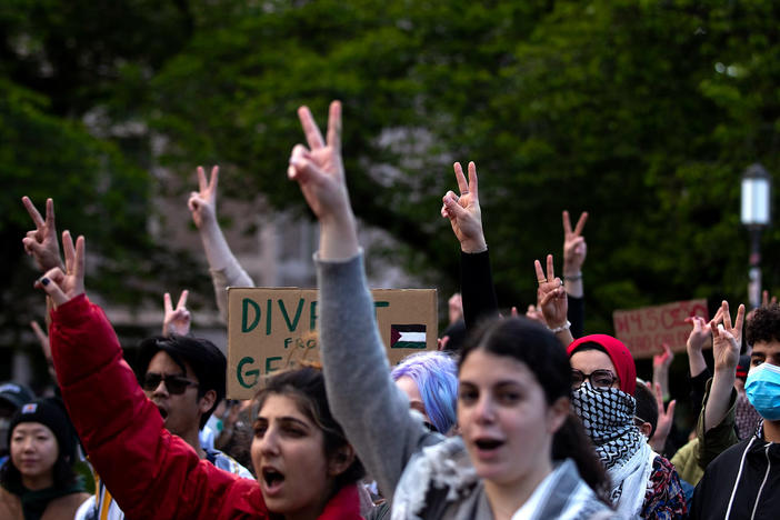 Students and protesters raise peace signs in the air while listening to speakers at the encampment for Palestine on Tuesday, May 7, 2024, at the University of Washington Quad in Seattle. Large crowds amassed ahead of a speech by Turning Point USA founder Charlie Kirk at the HUB on UW's campus.