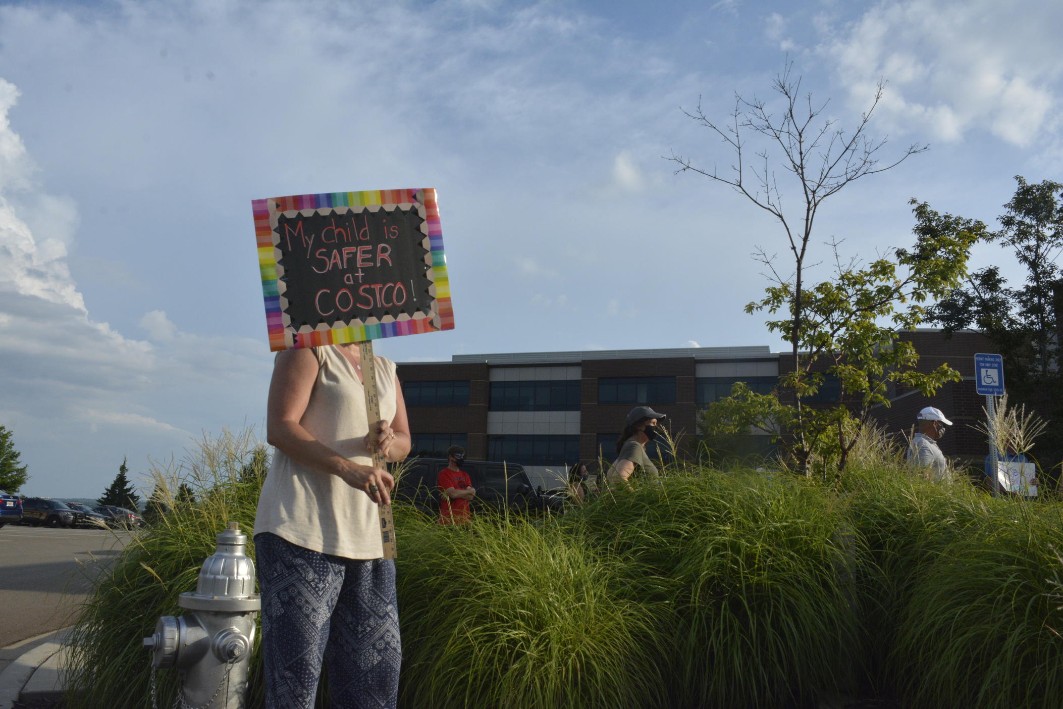 A person holds a sign that says "My child is safer at Costco" during a demonstration outside the July 16, 2020, Cherokee County School Board meeting. 