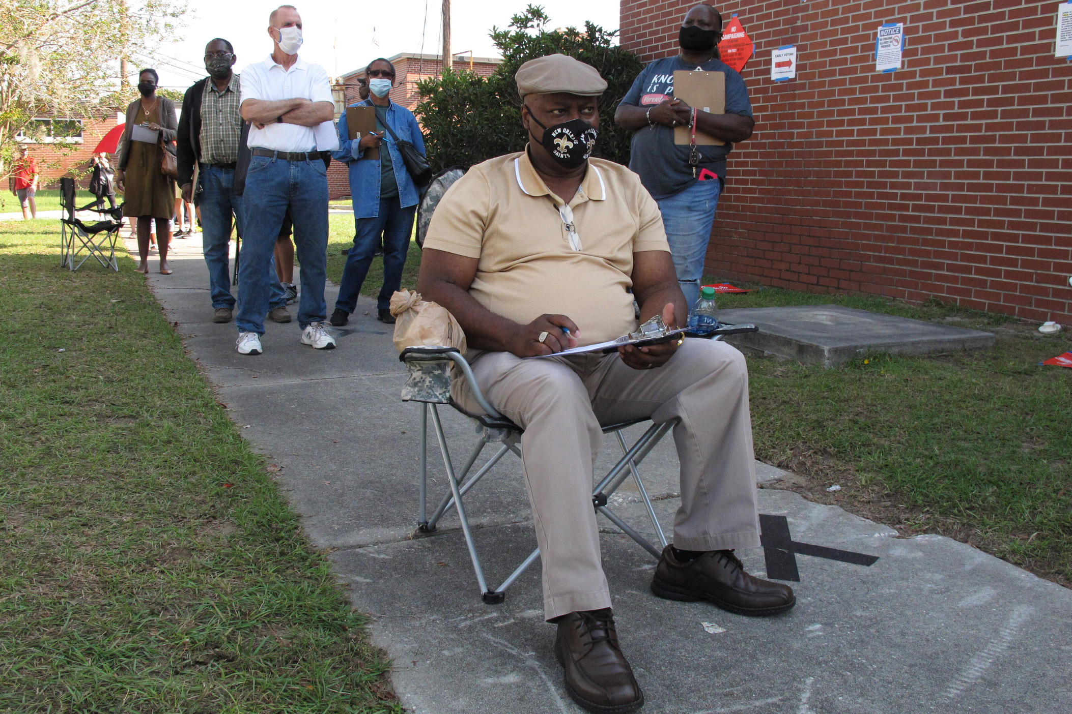 Richard Williams sits in a folding chair, filling out paperwork as he waits in line to vote early in Savannah, Georgia, on Wednesday, Oct. 14, 2020. Black Americans are going to the polls by the thousands and waiting in lines for hours to vote early in Georgia.