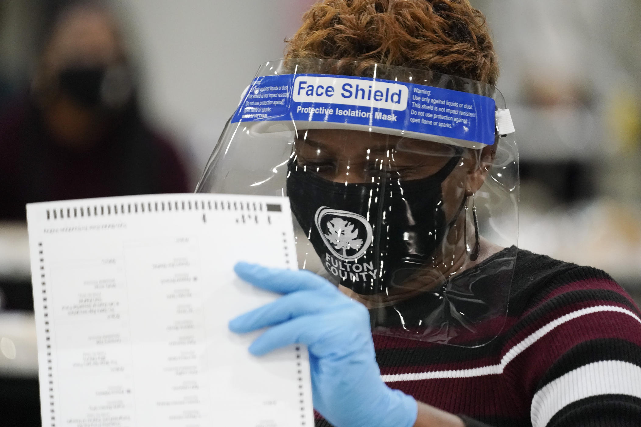 An official sorts through ballots during an audit at the Georgia World Congress Center on Saturday, Nov. 14, 2020, in Atlanta. Election officials in Georgia's 159 counties are undertaking a hand tally of the presidential race that stems from an audit required by state law. (AP Photo/Brynn Anderson)
