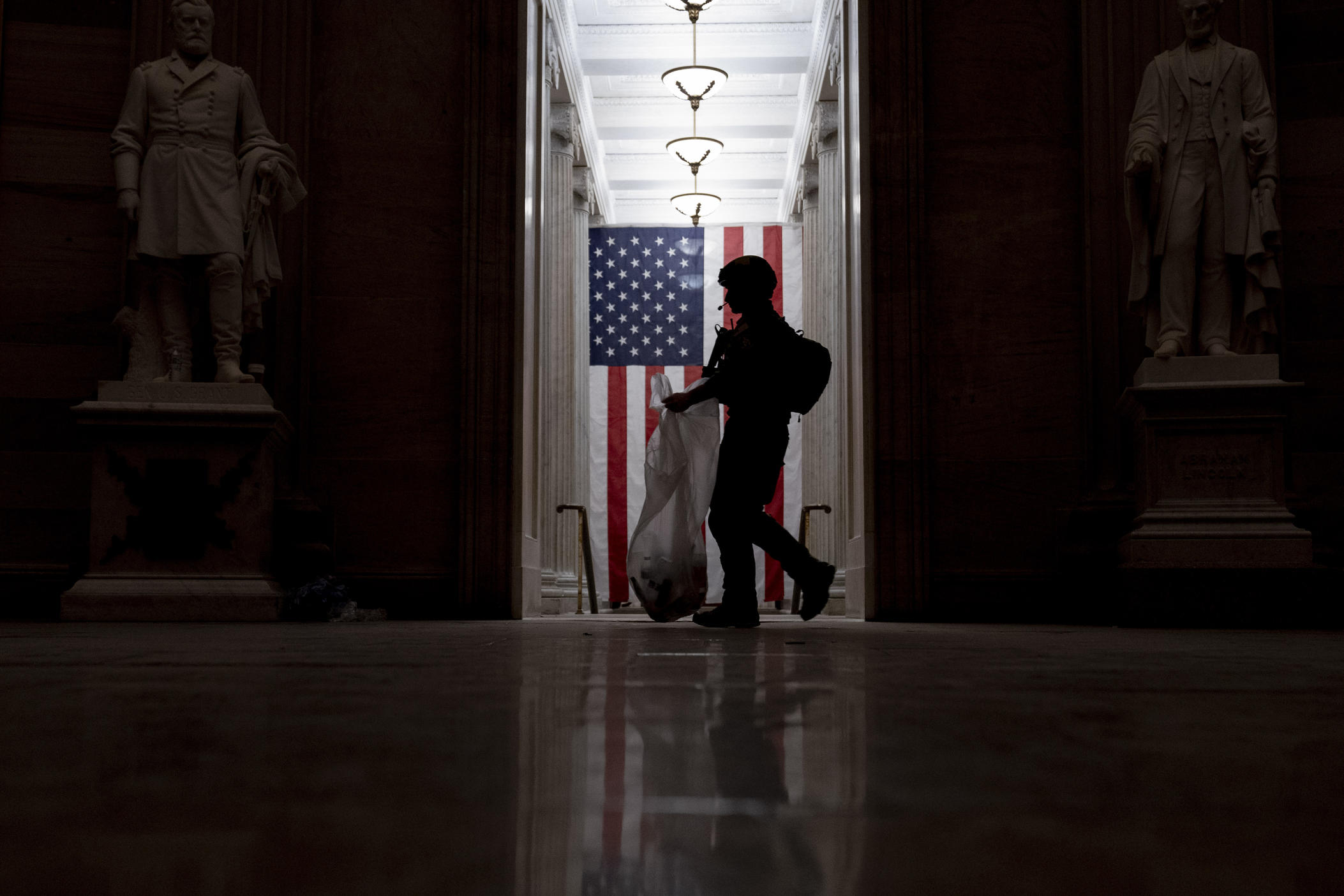 An ATF police officer cleans up debris and personal belongings strewn across the floor of the Rotunda in the early morning hours of Thursday, Jan. 7, 2021, after protesters stormed the Capitol in Washington, on Wednesday. 