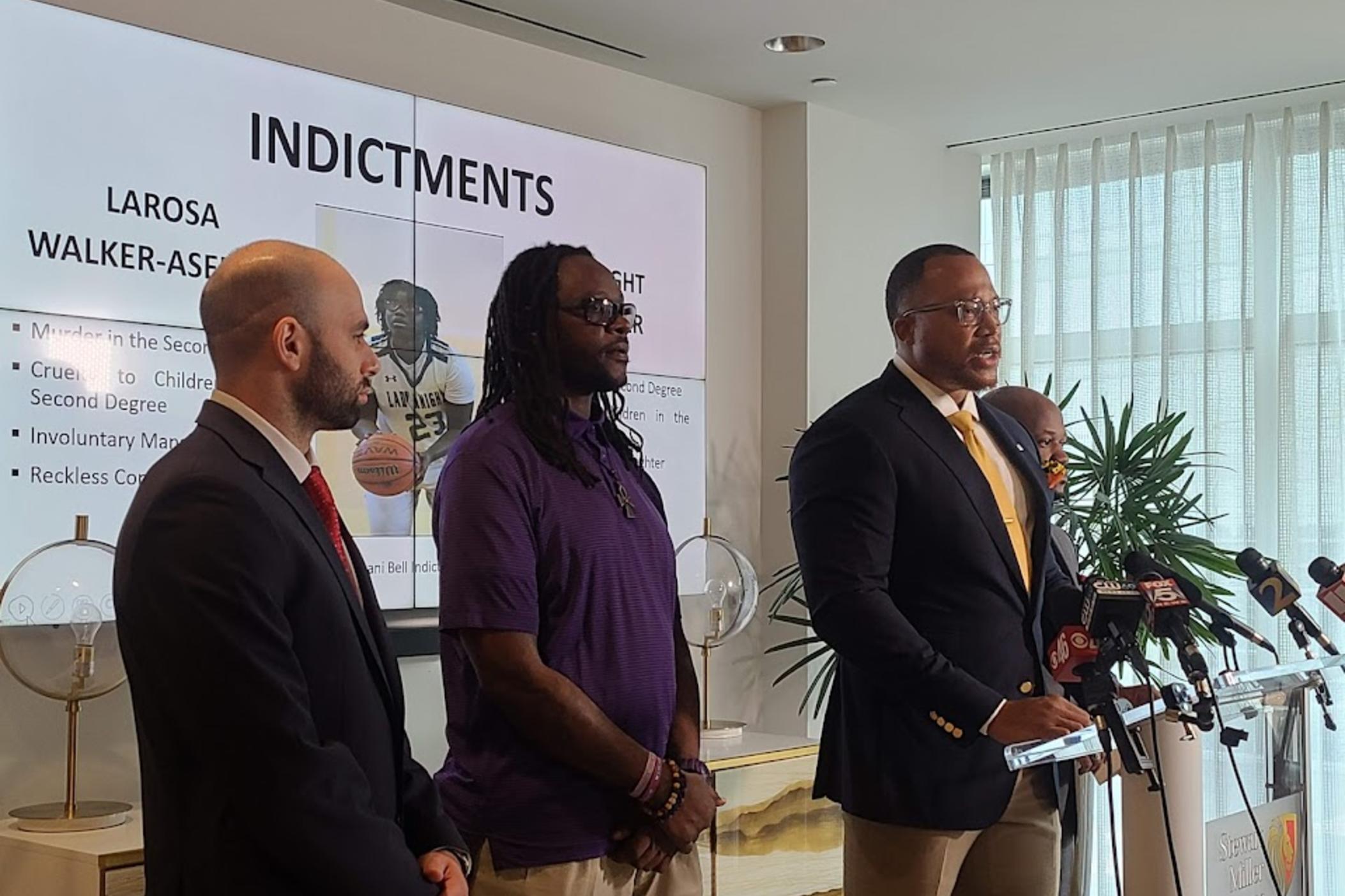 Imani Bell's father (in purple) stands with his attorneys, reacting to news of criminal charges against two high school basketball coaches involved in the heat-related death of the 16-year-old in August 2019.