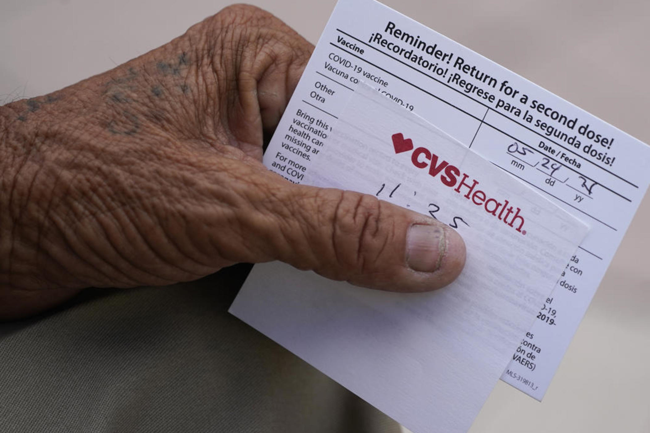 A man holds his vaccination reminder card after having received his first shot at a pop-up vaccination site next to Maximo Gomez Park, also known as Domino Park, Monday, May 3, 2021, in the Little Havana neighborhood of Miami.