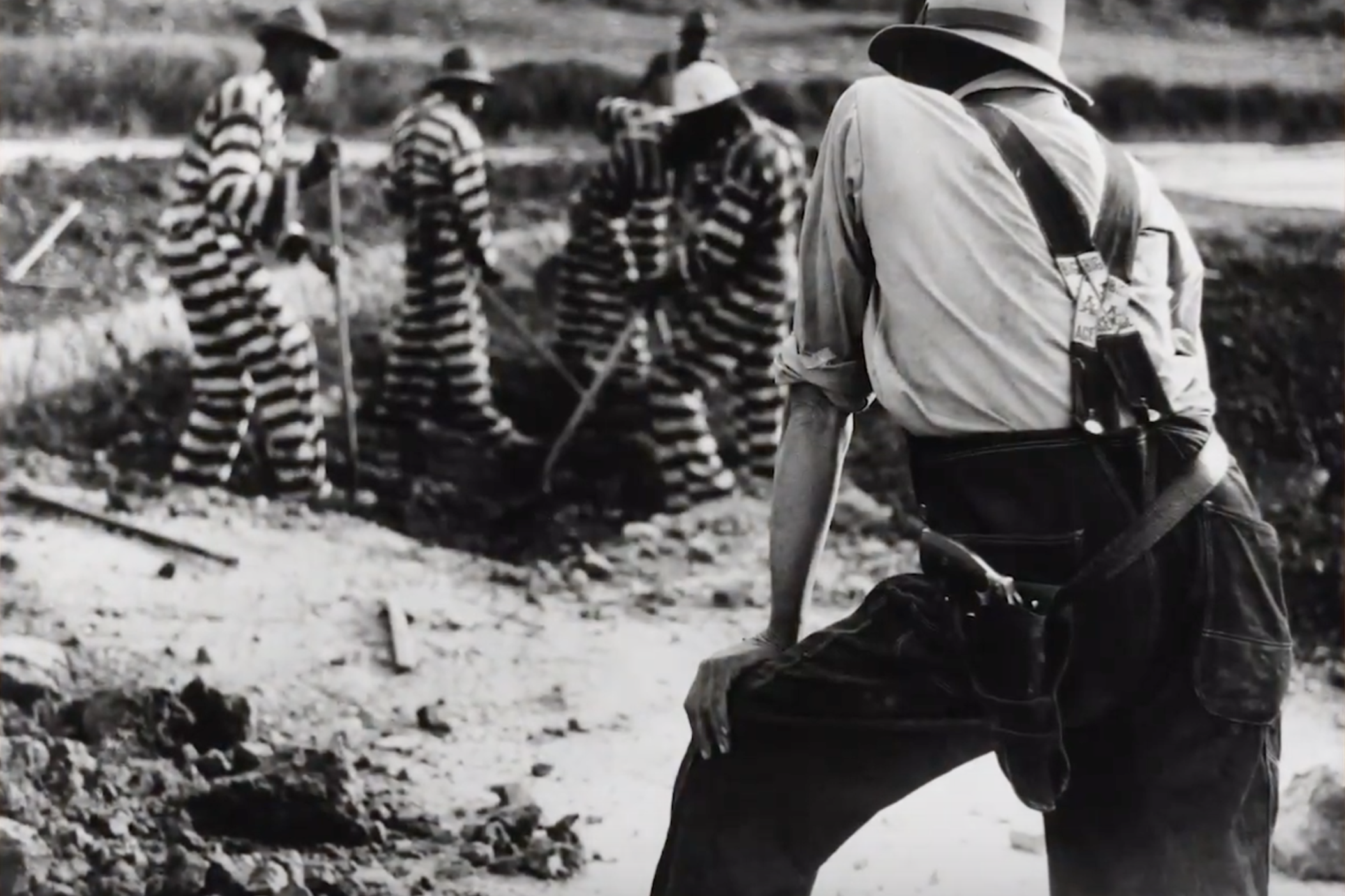 An armed guard oversees prisoners at a postbellum Georgia work camp.
