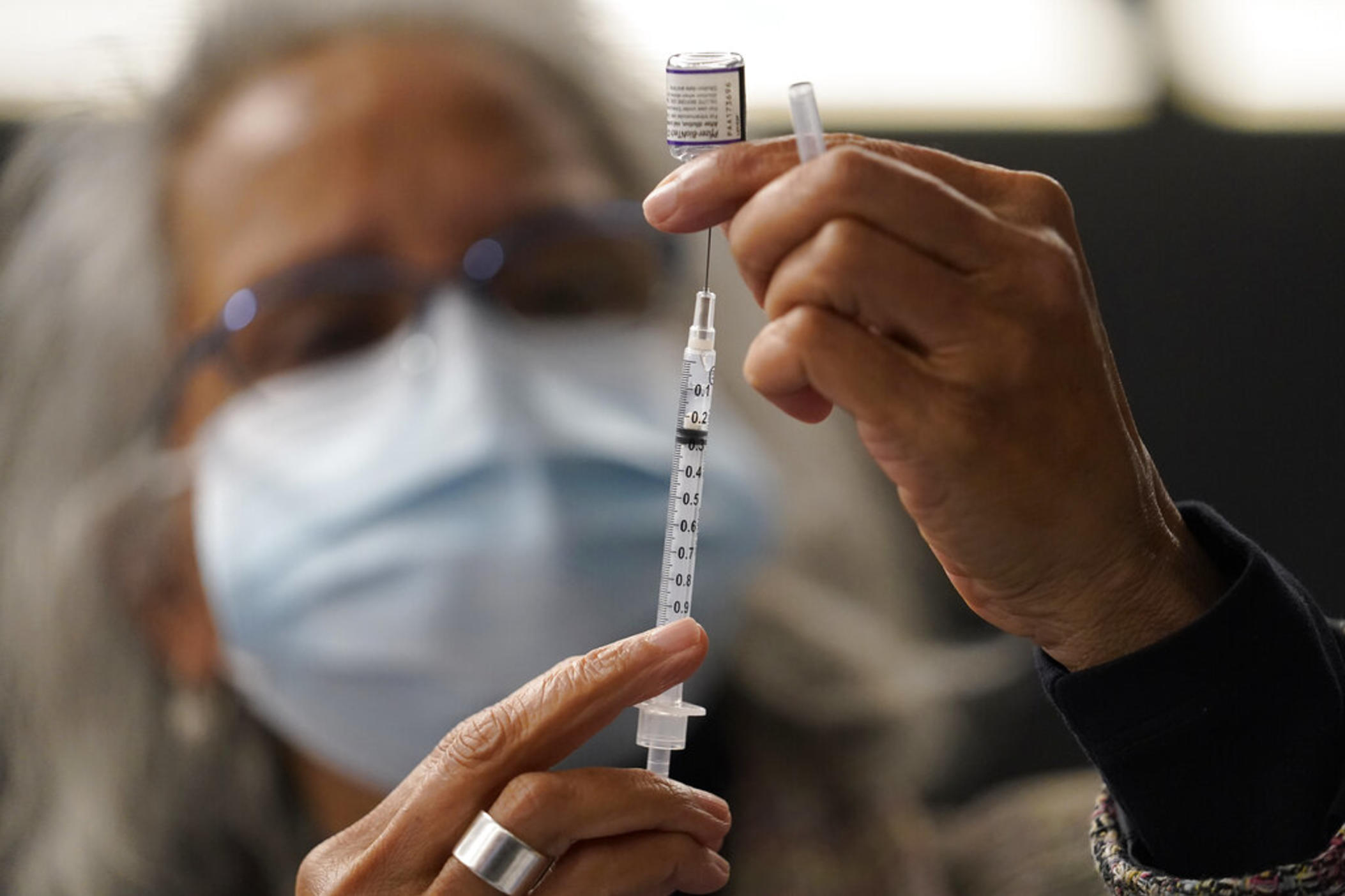Dr. Manjul Shukla transfers Pfizer COVID-19 vaccine into a syringe, Thursday, Dec. 2, 2021, at a mobile vaccination clinic in Worcester, Mass. As the U.S. recorded its first confirmed case of the omicron variant, doctors across the country are experiencing a more imminent crisis with a delta variant that is sending record numbers of people to the hospital in New England and the Midwest.