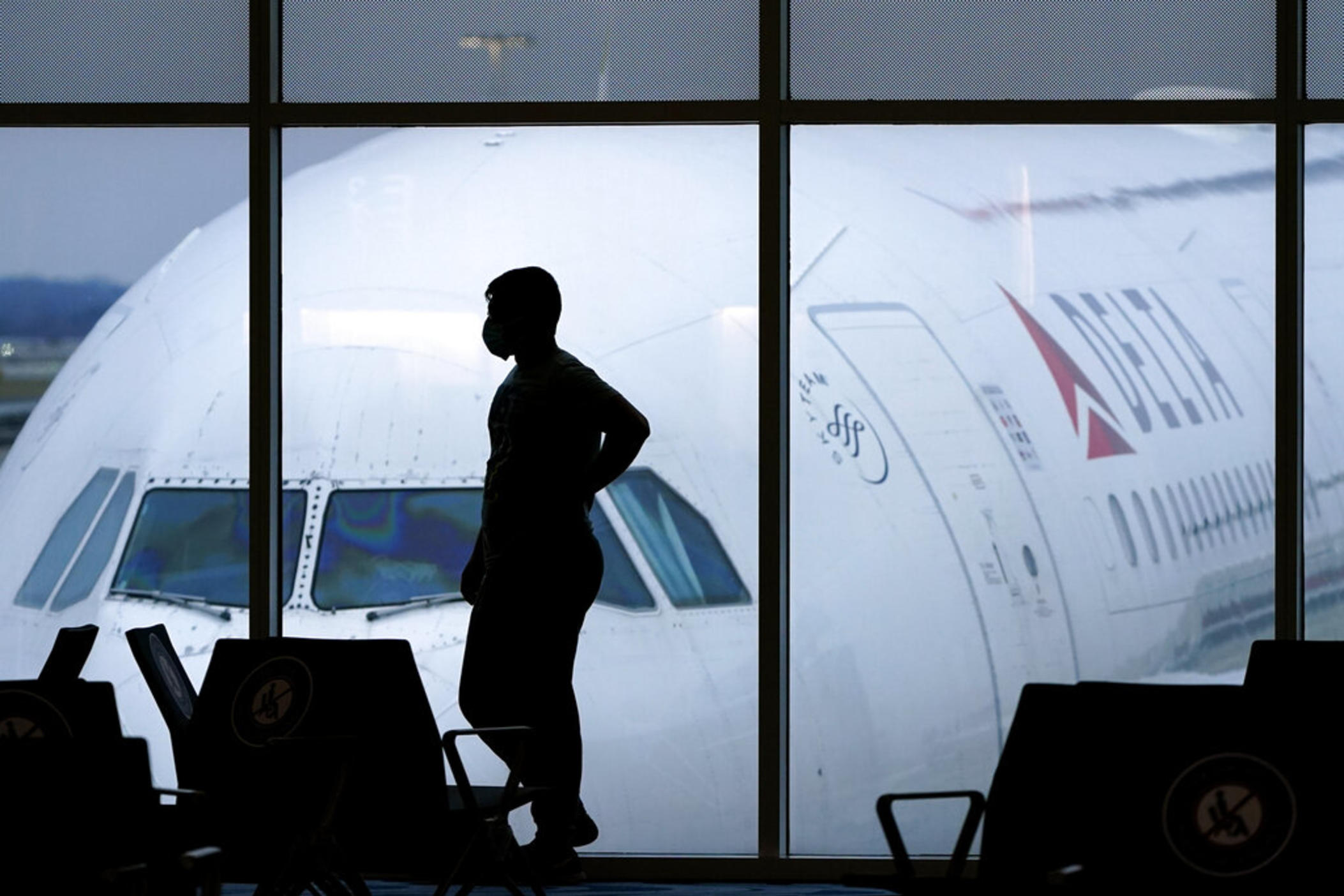 A passenger wears a face mask to help prevent the spread of the new coronavirus as he waits for a Delta Air Lines flight at Hartsfield-Jackson International Airport in Atlanta on Feb. 18, 2021. Delta Air Lines said Wednesday, Jan. 12, 2022, it will extend through 2023 the window for customers to rebook credits earned when they purchased but then canceled flights during the pandemic. 