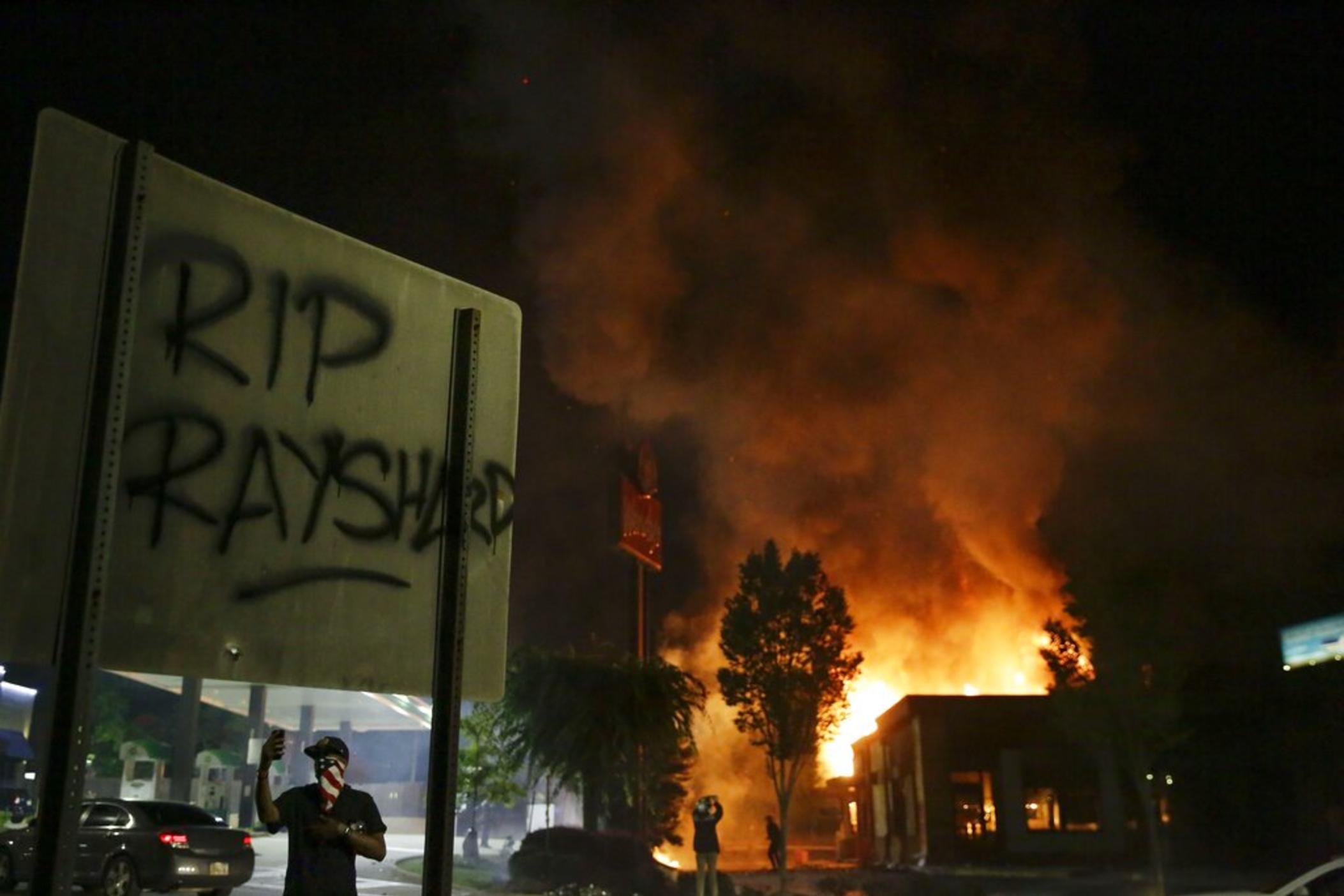 In this Saturday, June 13, 2020, file photo, "RIP Rayshard" is spray-painted on a sign as flames engulf a Wendy's restaurant where Rayshard Brooks was shot and killed by police in Atlanta. Three people have been indicted on arson charges in the burning of the Wendy’s restaurant in Atlanta where a police officer fatally shot Rayshard Brooks in June 2020.