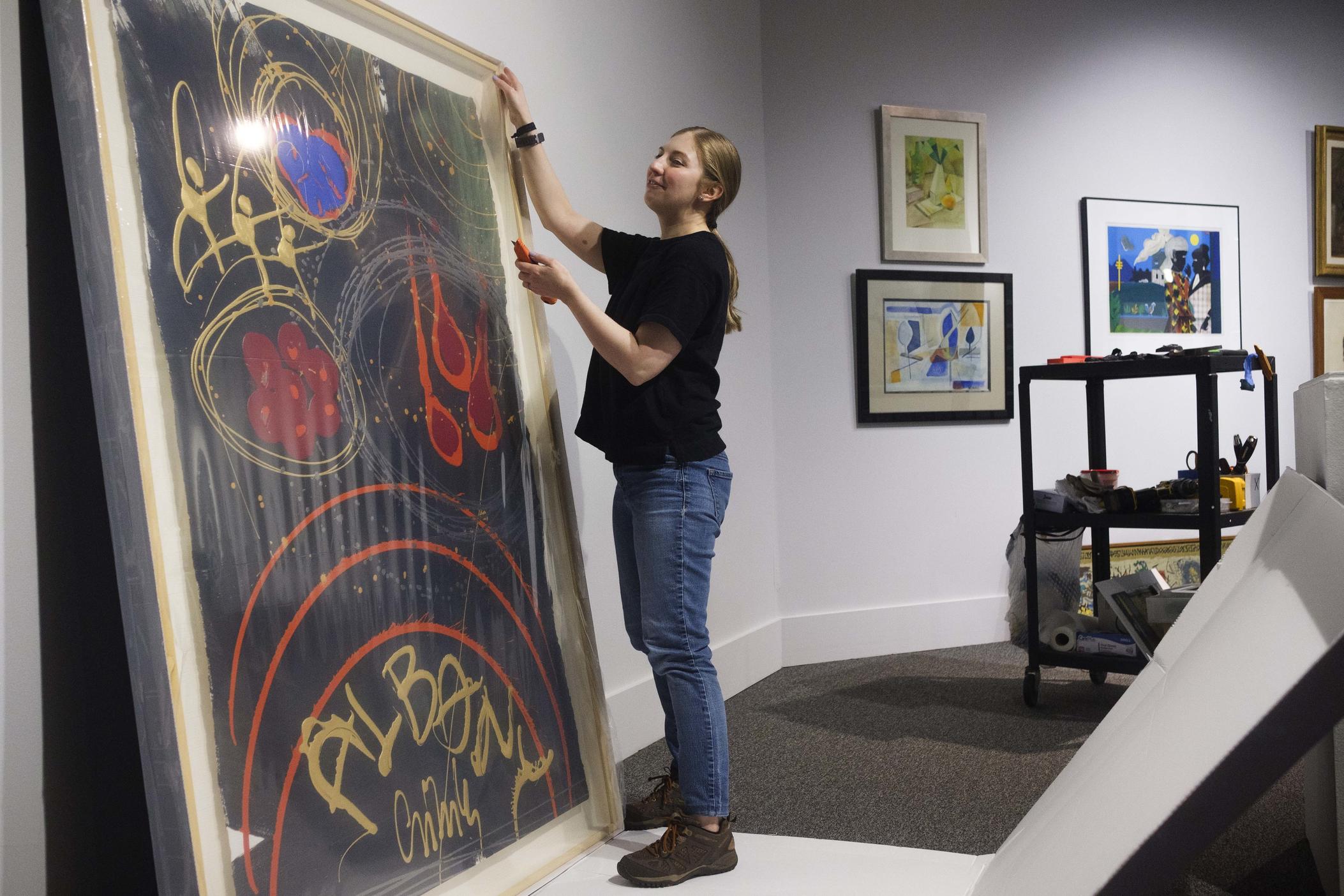 Albany Museum of Art curator Katie Dillard unpacks a repaired painting by glass artist Dale Chihuly while mounting the show titled "Homecoming" recently. 