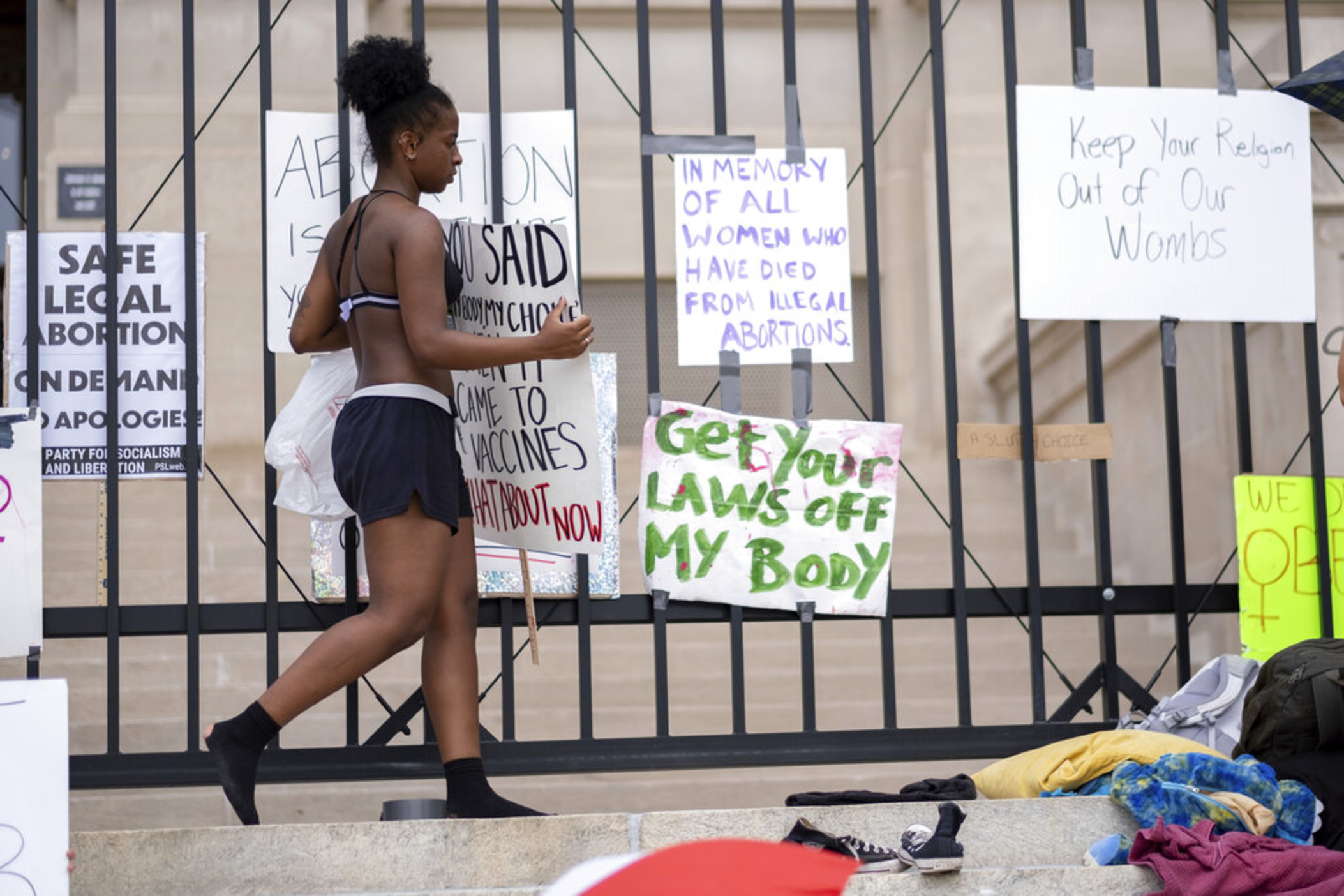 Nea Walker hangs a sign on the fence in front of the Georgia State Capitol while protesting the overturning of Roe v. Wade on Sunday, June 26, 2022.