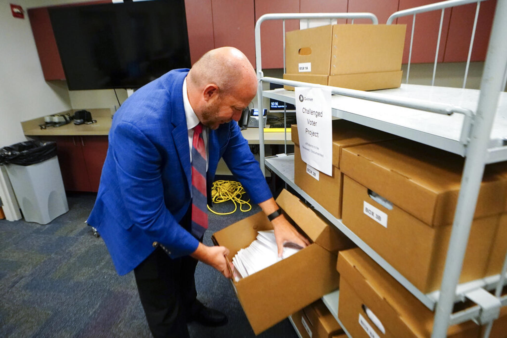 Gwinnett County elections supervisor Zach Manifold looks over boxes of voter challenges on Thursday, Sept. 15, 2022, in Lawrenceville, Ga. Manifold estimated his office has a month to log and research the challenges, before mail ballots go out for the November elections. “It is a tight window to get everything done,” he said.