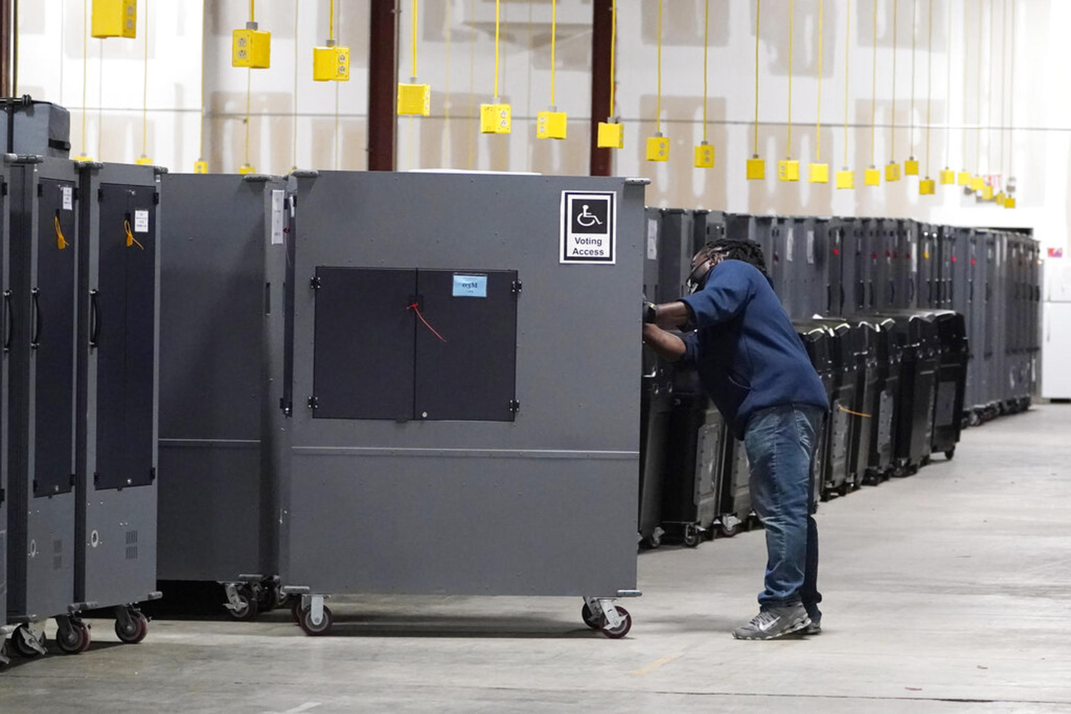 A worker returns voting machines to storage at the Fulton County Election preparation Center on Nov. 4, 2020 in Atlanta, Ga. The list of security breaches at local election offices since the 2020 election keeps growing, with investigations ongoing in at least three states, Colorado, Georgia and Michigan. Security experts say the breaches by themselves have not necessarily increased threats to the November elections, but say they increase the possibility that rogue election workers could access election equi