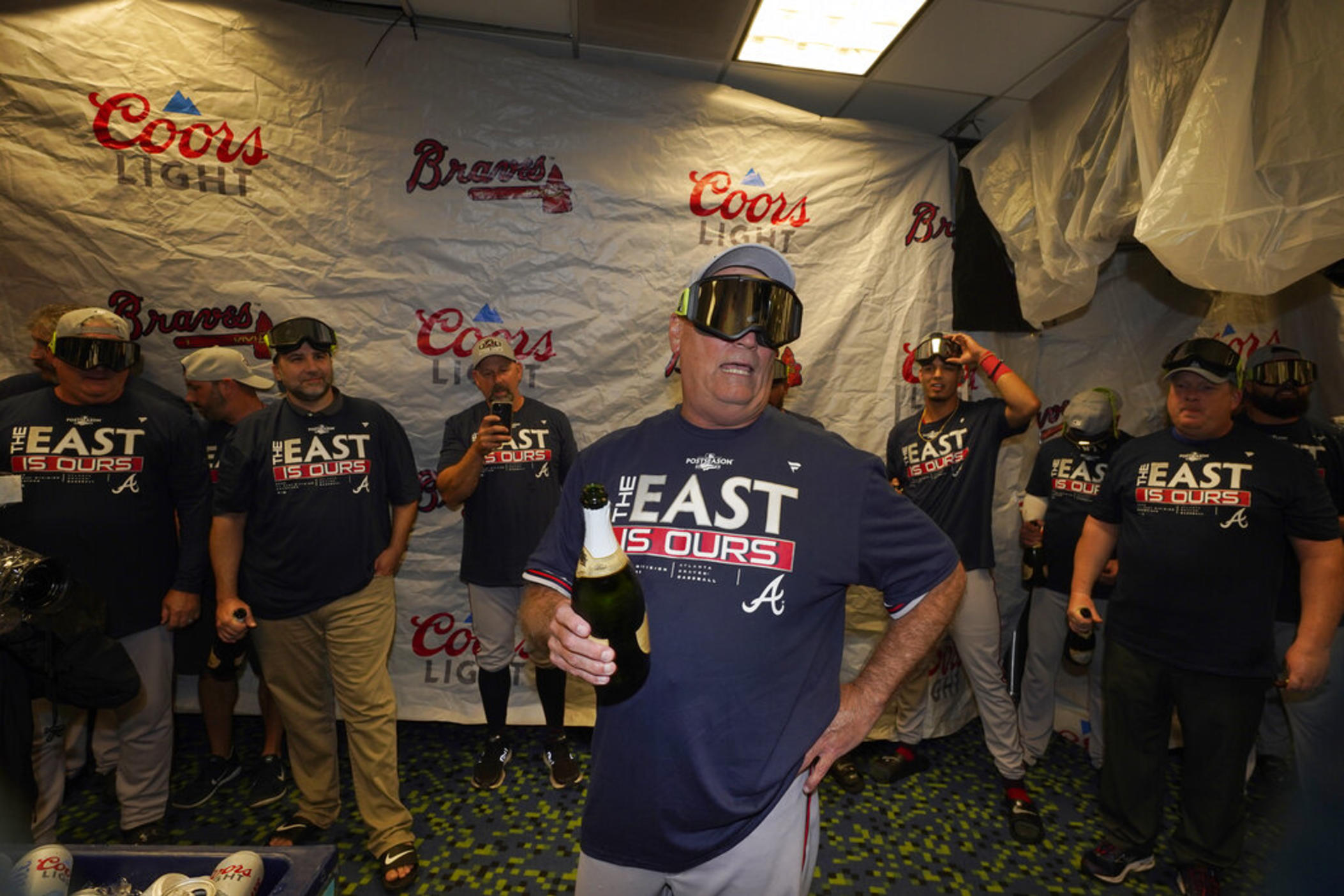 Atlanta Braves manager Brian Snitker, center, talks to players as they celebrate in the club house after clinching their fifth consecutive NL East title by defeating the Miami Marlins 2-1, in a baseball game, Tuesday, Oct. 4, 2022, in Miami. 