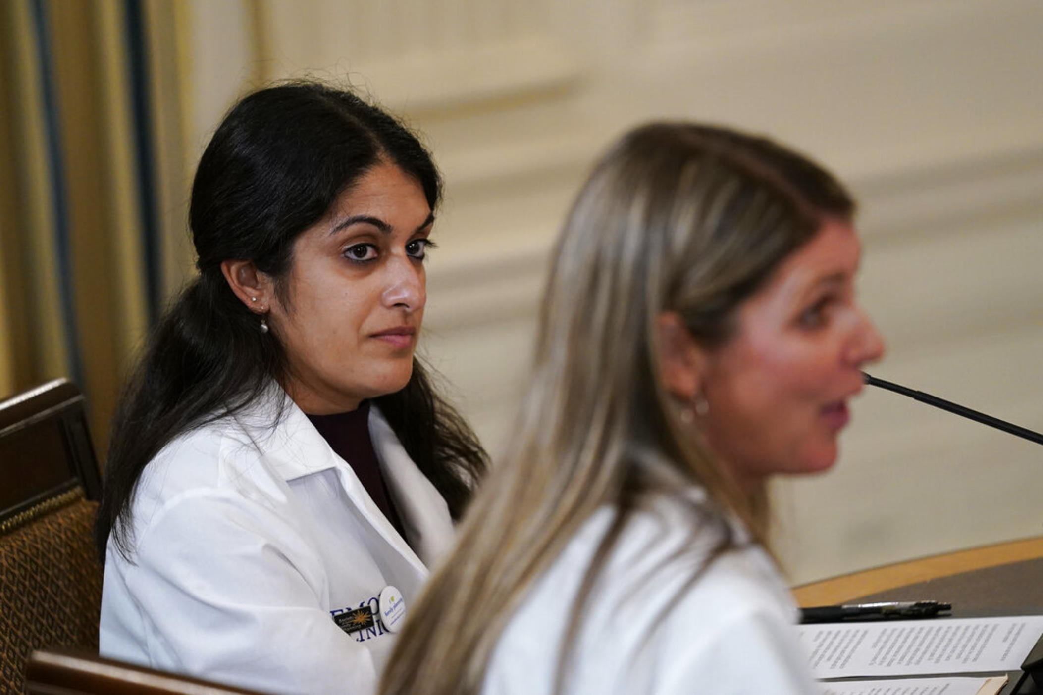 Dr. Nisha Verma, of Georgia, left, listens as Dr. Kristin Lyerly, right, from Wisconsin, speaks during a meeting of the reproductive rights task force in the State Dining Room of the White House in Washington, Tuesday, Oct. 4, 2022. President Joe Biden and Vice President Kamala Harris also attended the meeting. (AP Photo/Susan Walsh)