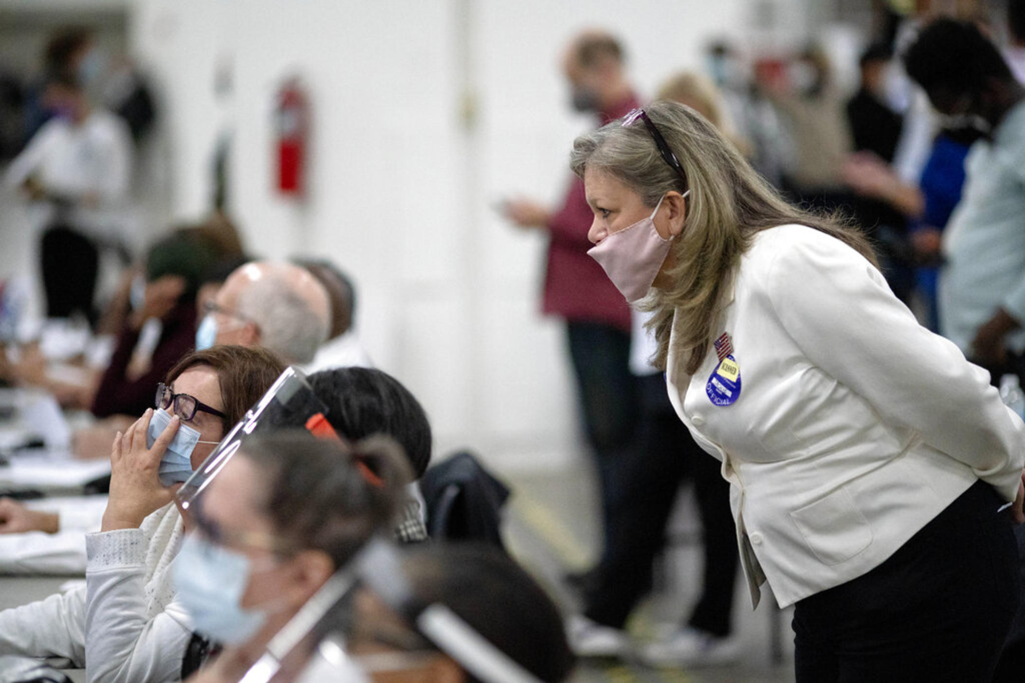 A Republican election challenger at right watches over election inspectors as they examine a ballot as votes are counted into the early morning hours, Nov. 4, 2020, at the central counting board in Detroit. Election officials across the country are bracing for a wave of confrontations in November as emboldened Republican poll watchers, many embracing former President Donald Trump's conspiracy theories about the 2020 election, flood polling places for the general election.