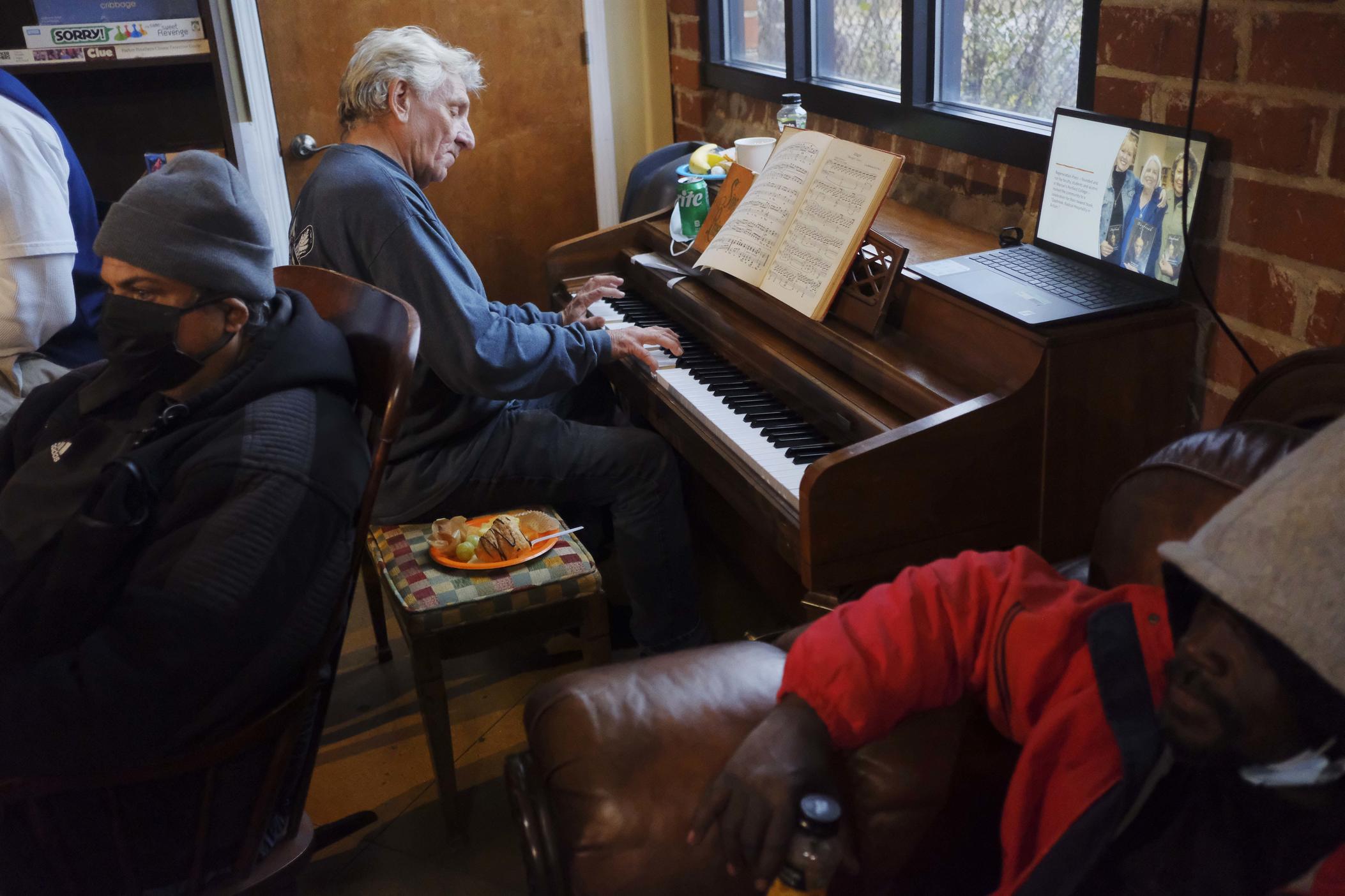 Randy Bedingfield plays the piano in a corner of the Daybreak Day Center during a reception celebrating the tenth anniversary of the facility which offers an array of services to the unhoused. Bedingfield, a regular, says he found the center after his parents died. "It hit during a particularly difficult time for me," he said. 