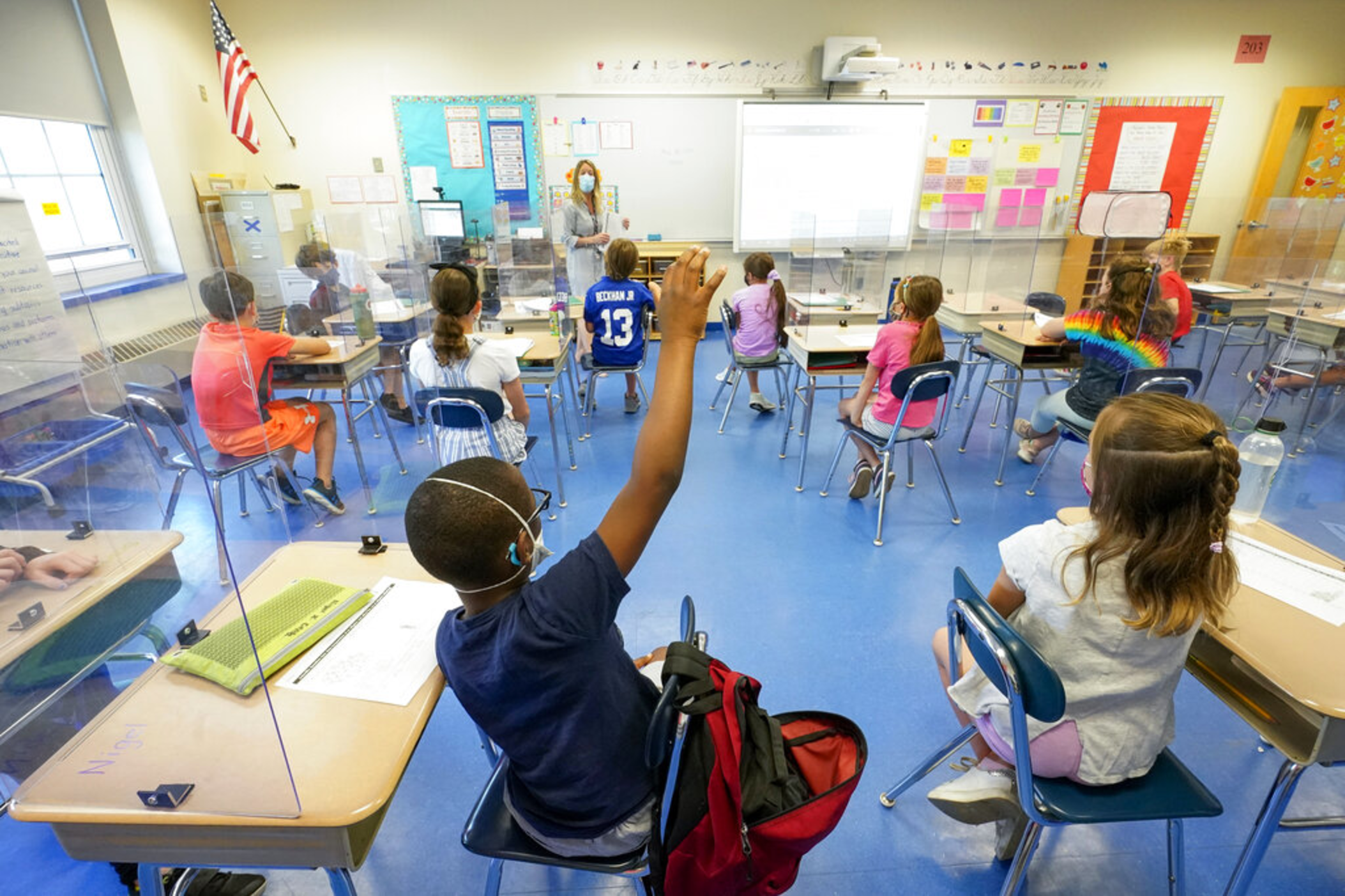 In this May 18, 2021, file photo, a teacher, center, and her third grade students wear face masks and are seated at proper social distancing spacing during as she conducts her class in Rye, N.Y.