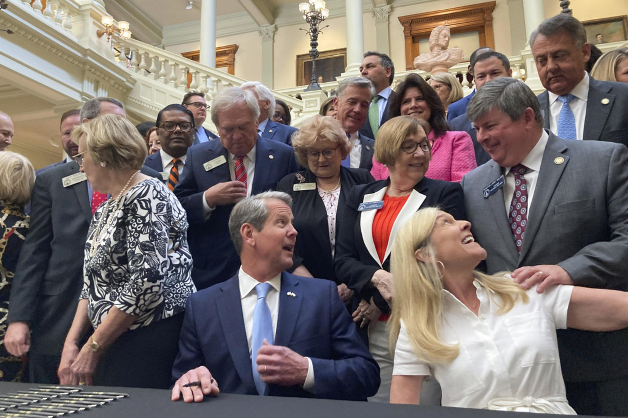 Georgia Gov. Brian Kemp, bottom center, speaks to state Sen. Larry Walker III, R-Perry, right, before signing bills into law at the state Capitol on Tuesday, May 2, 2023, in Atlanta. Georgia's state government will for the first time run its own marketplace for individual health insurance under a law that Republican Gov. Kemp signed. 
