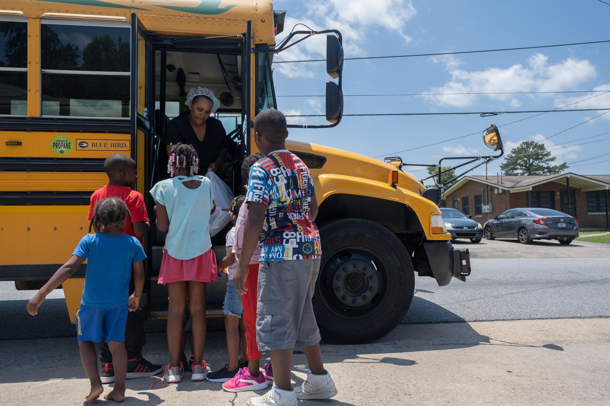 Sheena Hartry hands out lunch bags to kids at a neighborhood in south Macon during the second to last week of the Bibb County School District's mobile summer lunch program.