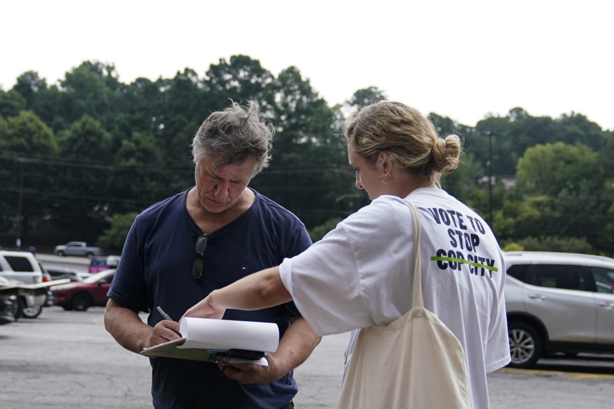 Canvasser Sienna Giraldi, 26, right, talks to an Atlanta resident, left, Thursday, July 20, 2023, in Atlanta. Activists with the Stop Cop City Vote Coalition are trying to get the signatures of more than 70,000 Atlanta residents by Aug. 14 to force a referendum allowing voters to decide the fate of a proposed police and firefighter training center.