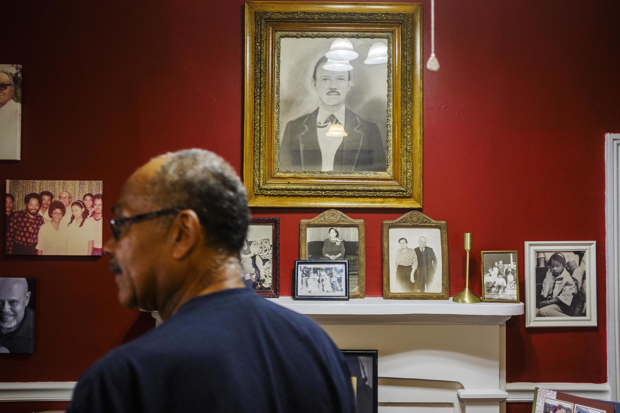    Mark Smith among photos of generations of his family in the home he grew up in in Hancock County. The house now belongs to his brother, Blaine, and is on one of the pieces of property the Sandersville Railroad wants a piece of for a shortline railroad.  