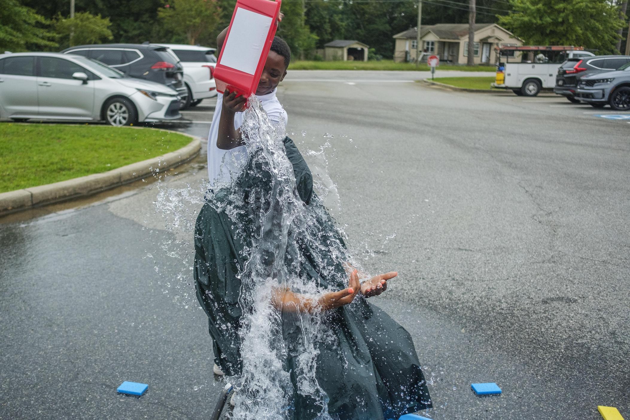Principal Kizzie Lott, seated, endures a dousing by one of her students at Bruce Elementary School in Macon in part as a reward for his good attendance. 