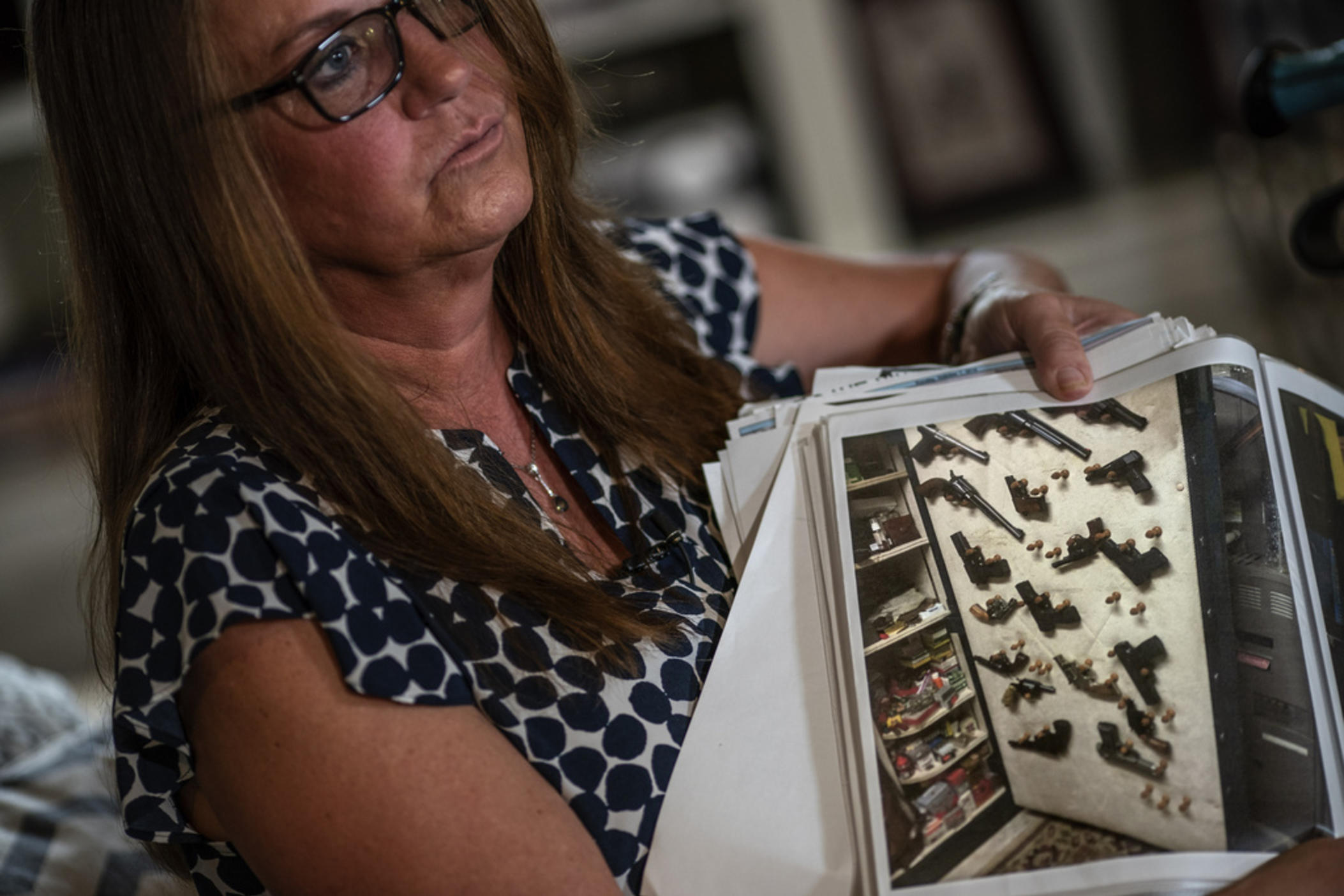 Janet Paulsen shows a photo of some of the dozens of guns that police seized from her estranged husband days before he ambushed her at their home in 2015. Paulsen still lives in the home in Acworth, Ga., Monday, Aug. 7, 2023. “Every step of the way it seemed like his rights were more important … than mine and my children’s,” she says. 