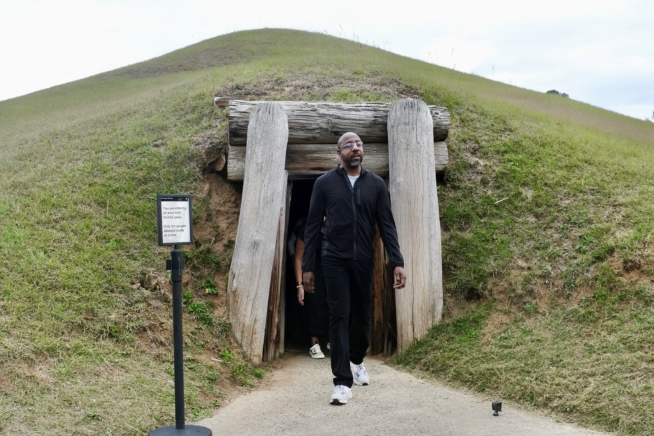 Senator Raphael Warnock exits the Earth Lodge, a relic of Mississippian culture from over 1,000 years ago, during his tour of the Ocmulgee National Historic Park on Nov. 20, 2023.