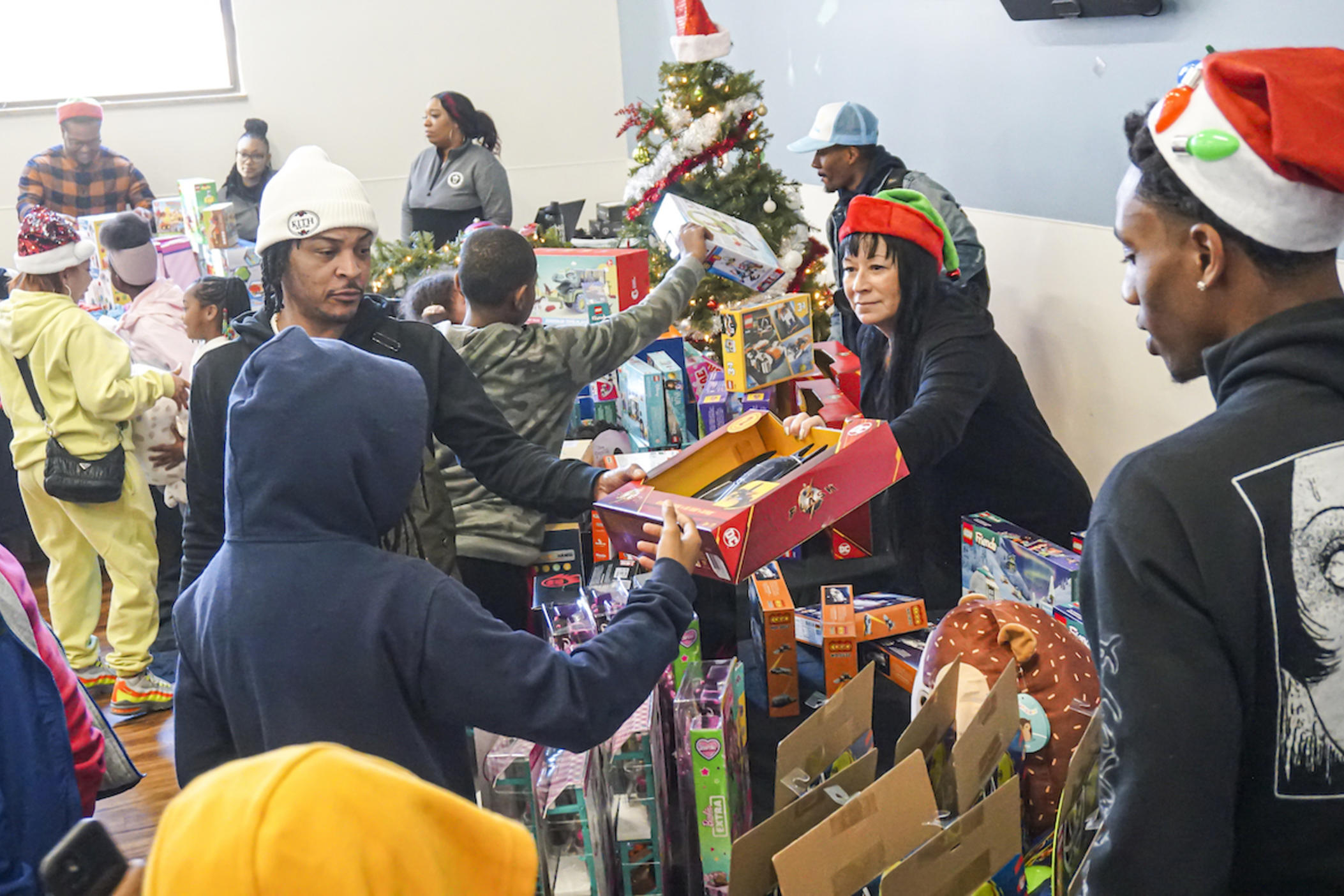 Atlanta rapper and actor Tip 'T.I.' Harris (in white cap) helps volunteers distribute holiday gifts to attendees at My Sister's House,  the women and children's shelter of the Atlanta Mission the week before Christmas 2023.