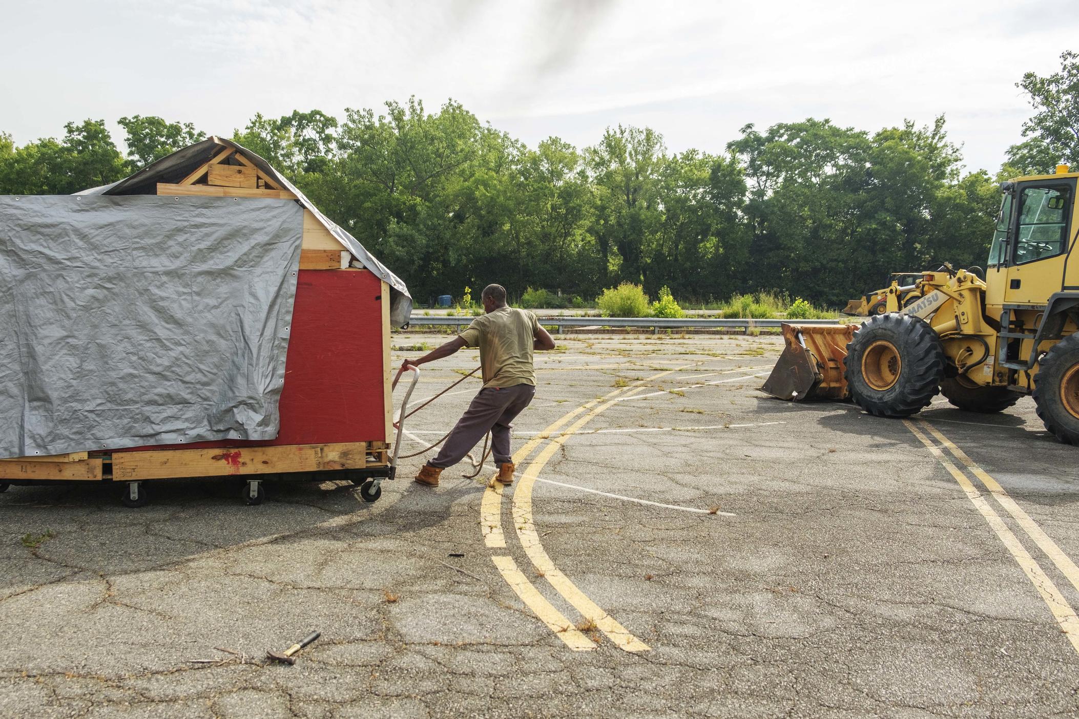A man attempts to roll his home out of the way of a front end loader during a sweep of a homeless encampment in Macon in June of 2022.