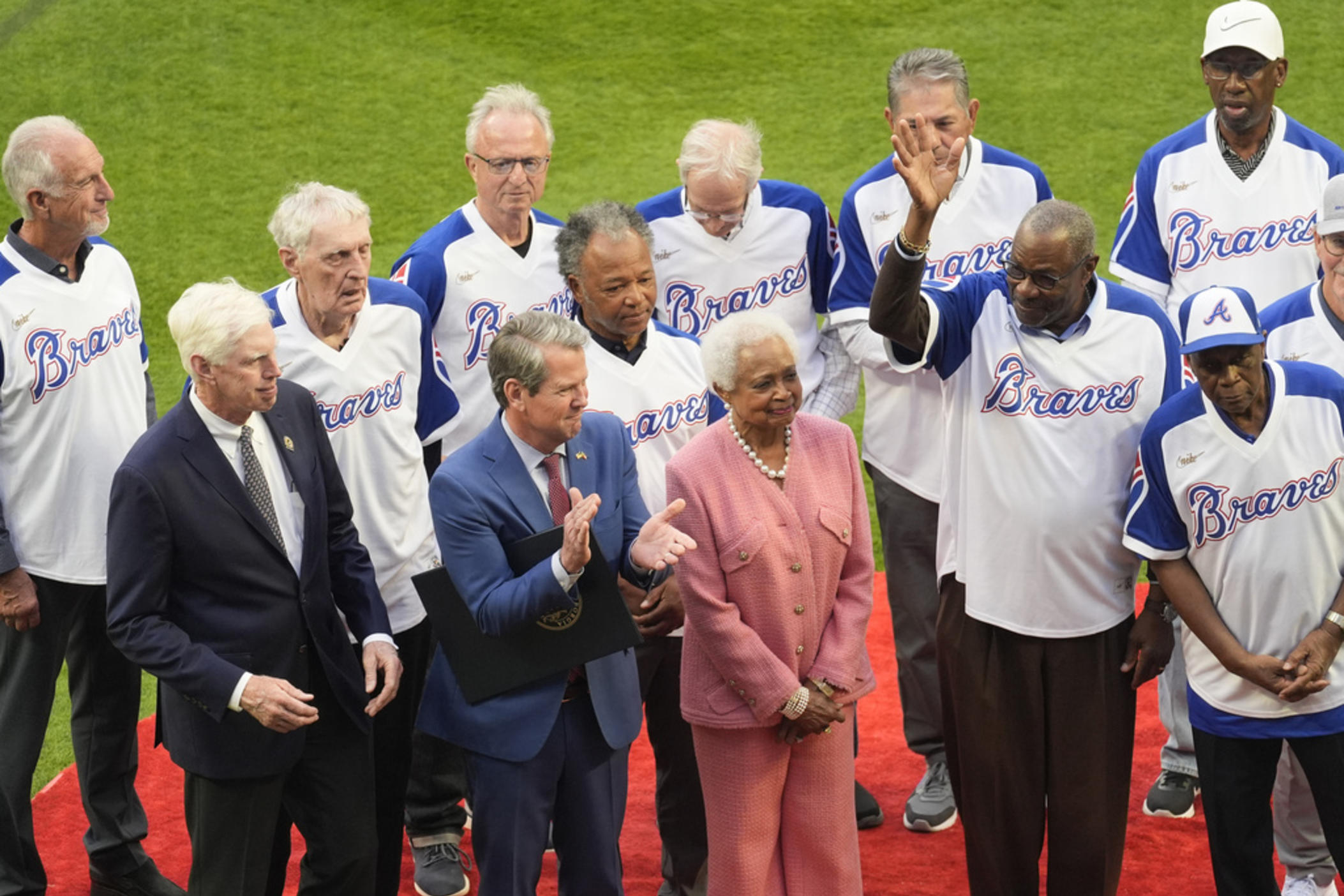 Billye Aaron, wife of the late Hank Aaron stands with Georgia Gov. Brian Kemp, second from left, Atlanta Braves chairman and CEO Terry McGuirk, left, Dusty Baker, right and players from the 1974 Atlanta Braves team during a ceremony to mark the 50th anniversary of Aaron breaking Babe Ruth's home run record team before a baseball game against the New York Mets Monday, April 8, 2024, in Atlanta. 