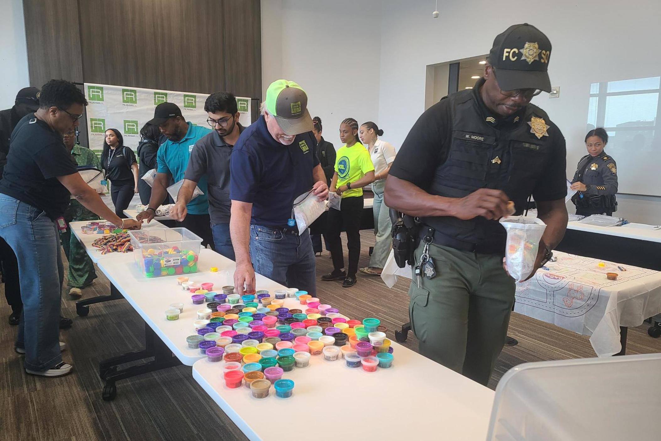 Volunteers from H.J. Russell & Company, Atlanta Police Department, and Fulton County Sheriff's Office assemble kits full of toys to calm and distract children during emergencies on April 30, 2024.