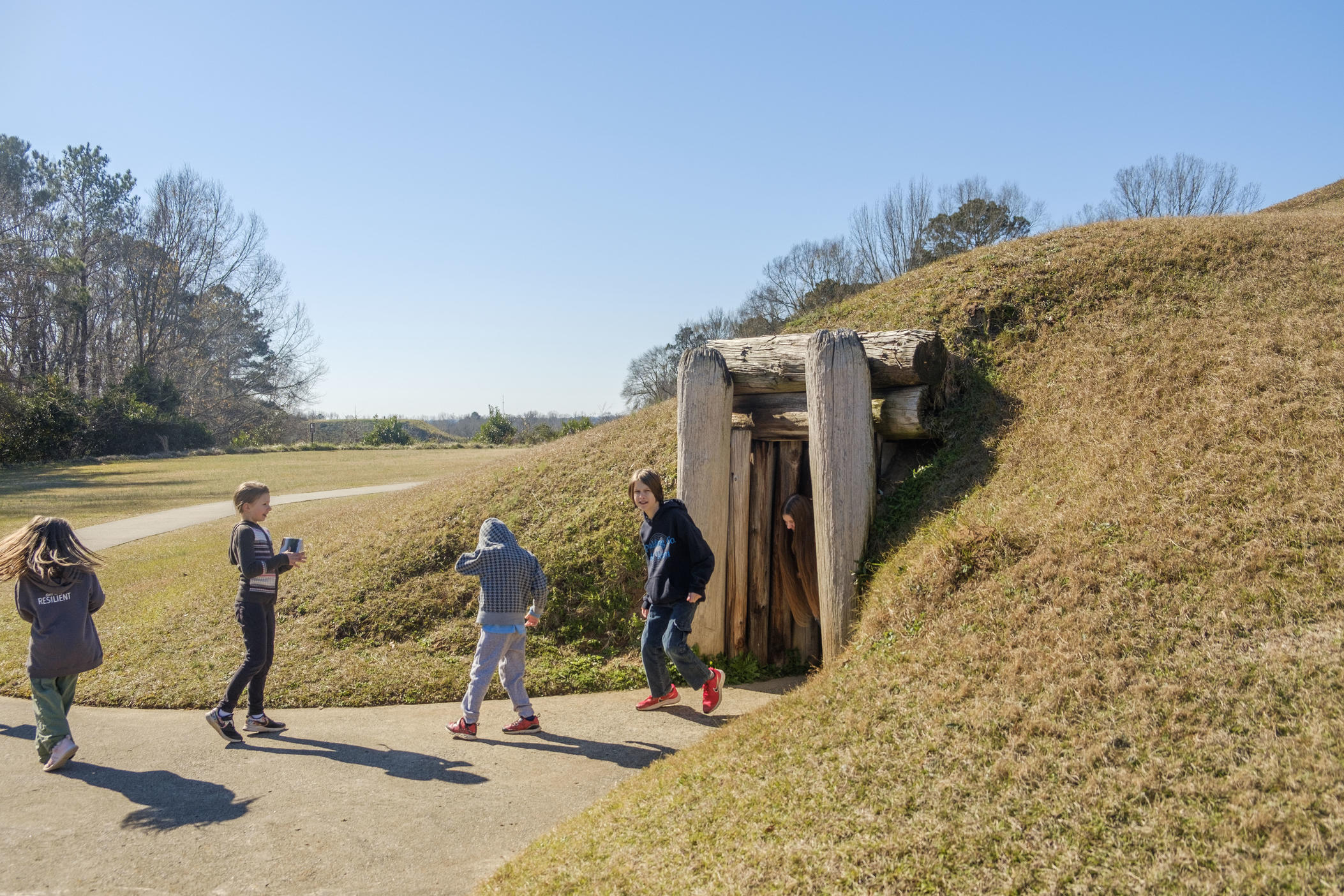 Students leave the Earth lodge, thought to be used historically as a council space, at the Ocmulgee Mounds National Historic Park in Macon in 2022. 
