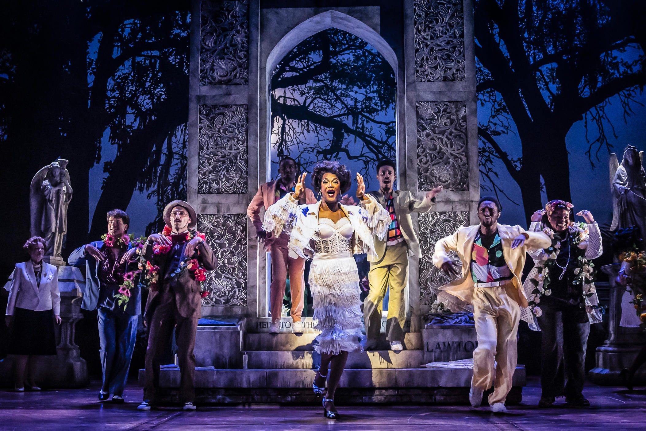 J. Harrison Ghee performs as The Lady Chablis in a scene set at Savannah's Bonaventure Cemetery, surrounded by ensemble members of the cast.