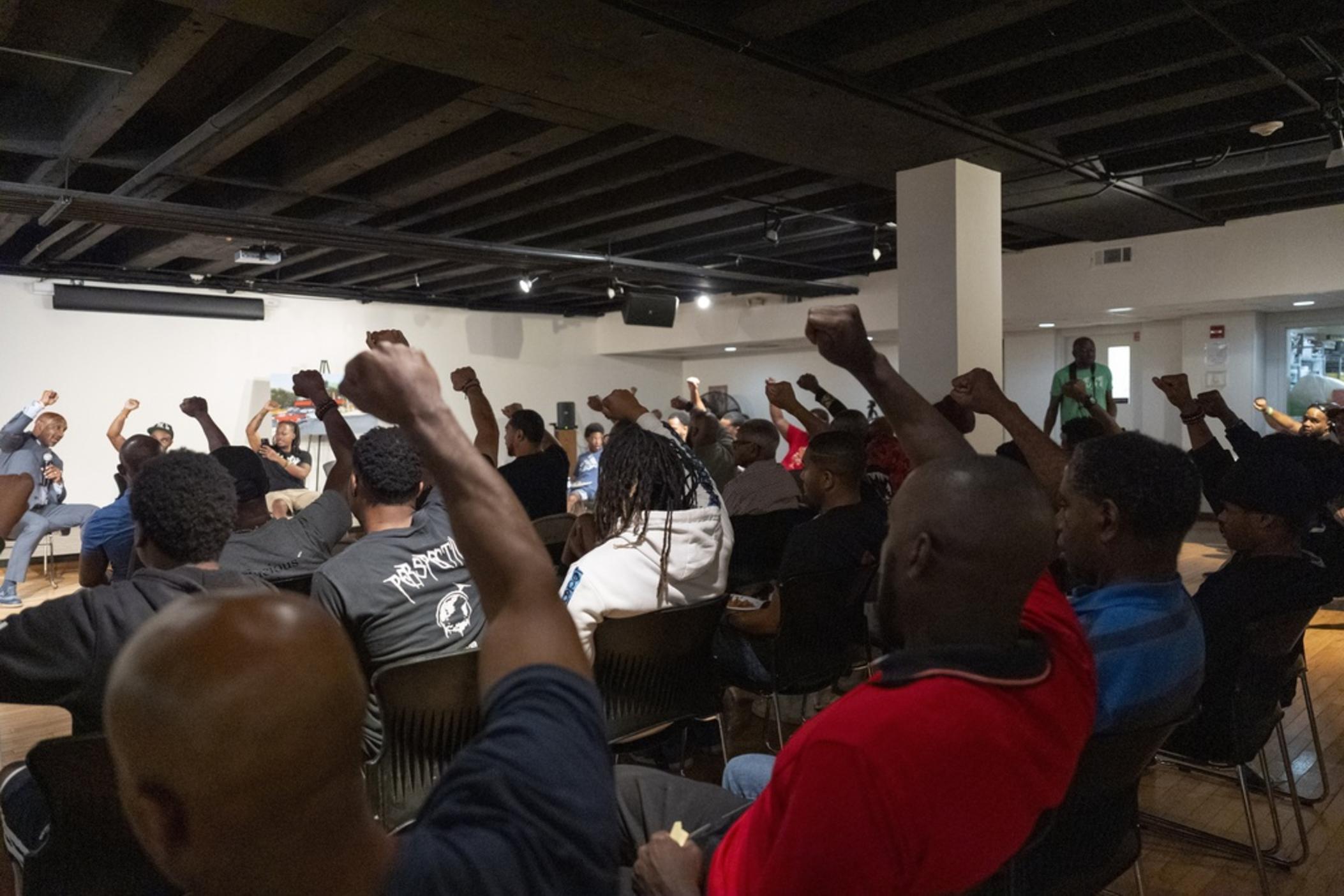 Panelists and attendees raise their fists during a Black Man Lab meeting to discuss the candidacy of Vice President Kamala Harris, Monday, July 22, 2024, in Atlanta. The Black Man Lab hosts weekly gatherings with the purpose of providing an intergenerational safe space for Black men and boys. 