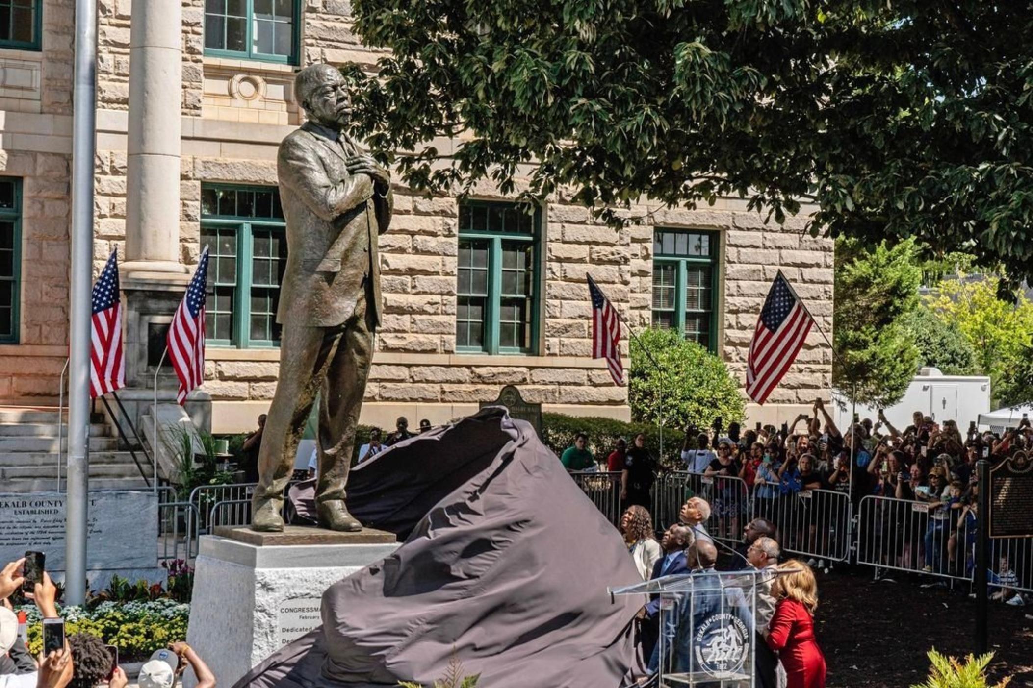 Dignitaries pull the cover off the statue honoring the late civil rights leader and congressman John Lewis during its unveiling ceremony in Decatur, Ga., on Saturday, Aug 24, 2024.