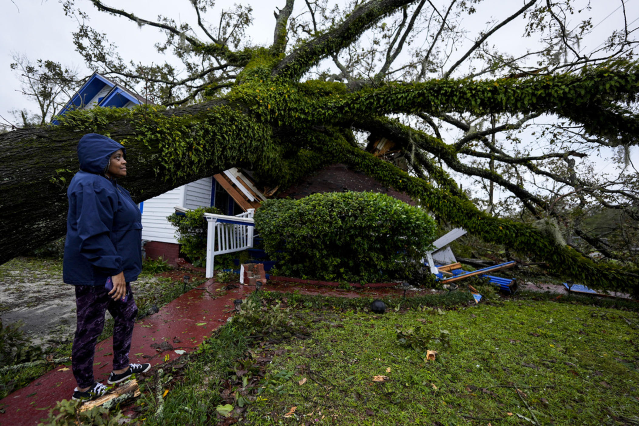 Ronda Bell looks on after an Oak tree landed on her 100-year-old home after Hurricane Helene moved through, Friday, Sept. 27, 2024, in Valdosta, Ga. 