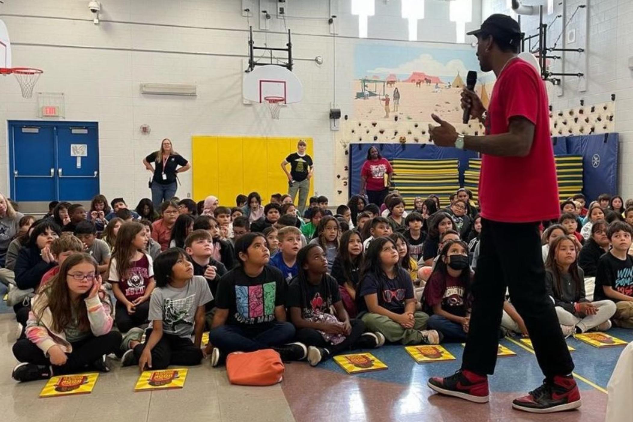 Malcolm Mitchell speaks to a gym full of elementary aged children.