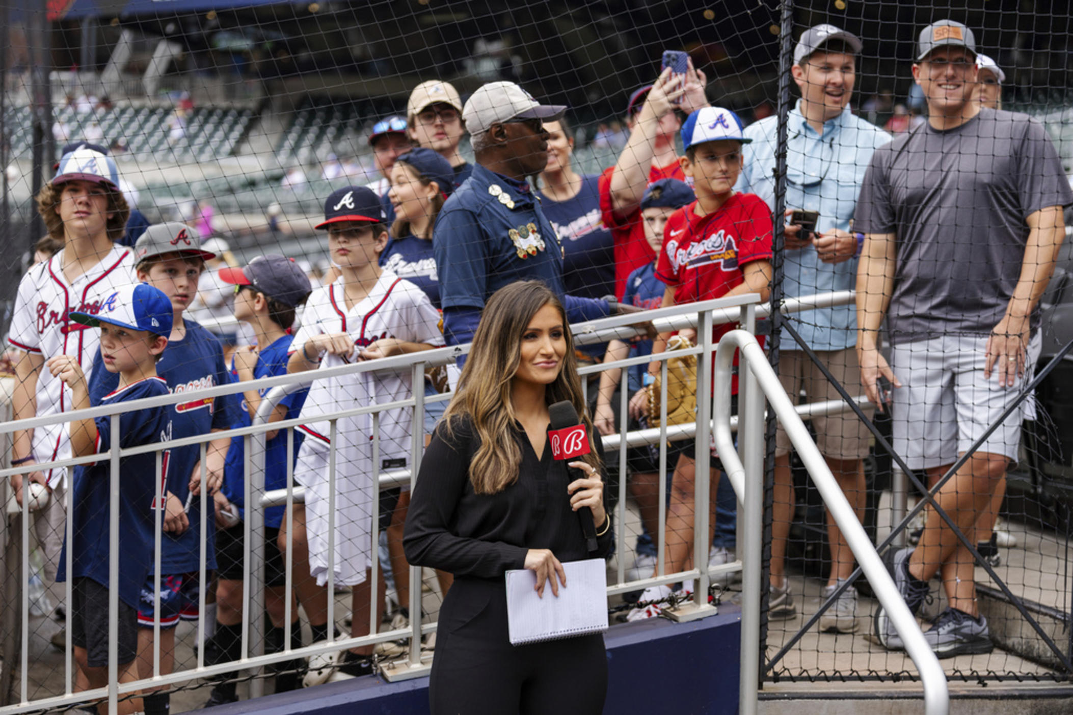 Bally reporter, Hanna Yates, broadcasts her pregame with fans standing behind her waiting for autographs before the start of a baseball game between the New York Mets and the Atlanta Braves, Monday, Sept. 30, 2024, in Atlanta. 