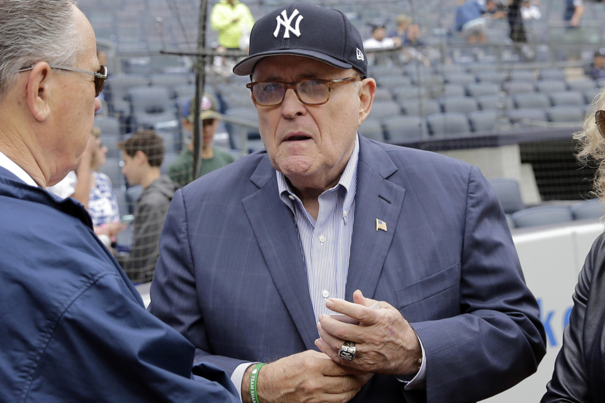 Rudy Giuliani, wearing one of his Yankees' championship rings, talks with people on the field before the game between the New York Yankees and the Houston Astros at Yankee Stadium, May 28, 2018 in New York. 