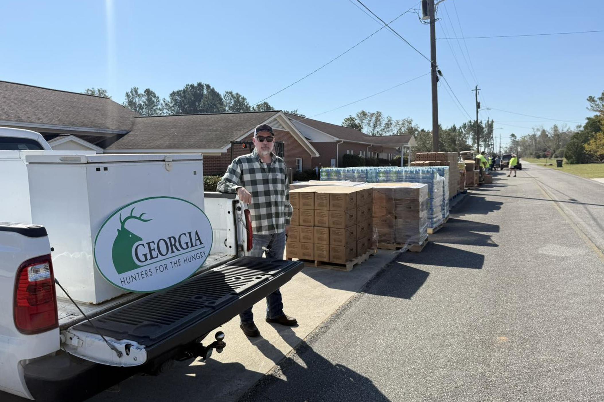 A man stands next to a truck with a Georgia Hunters for the Hungry logo, and eight hundred pounds of venison.