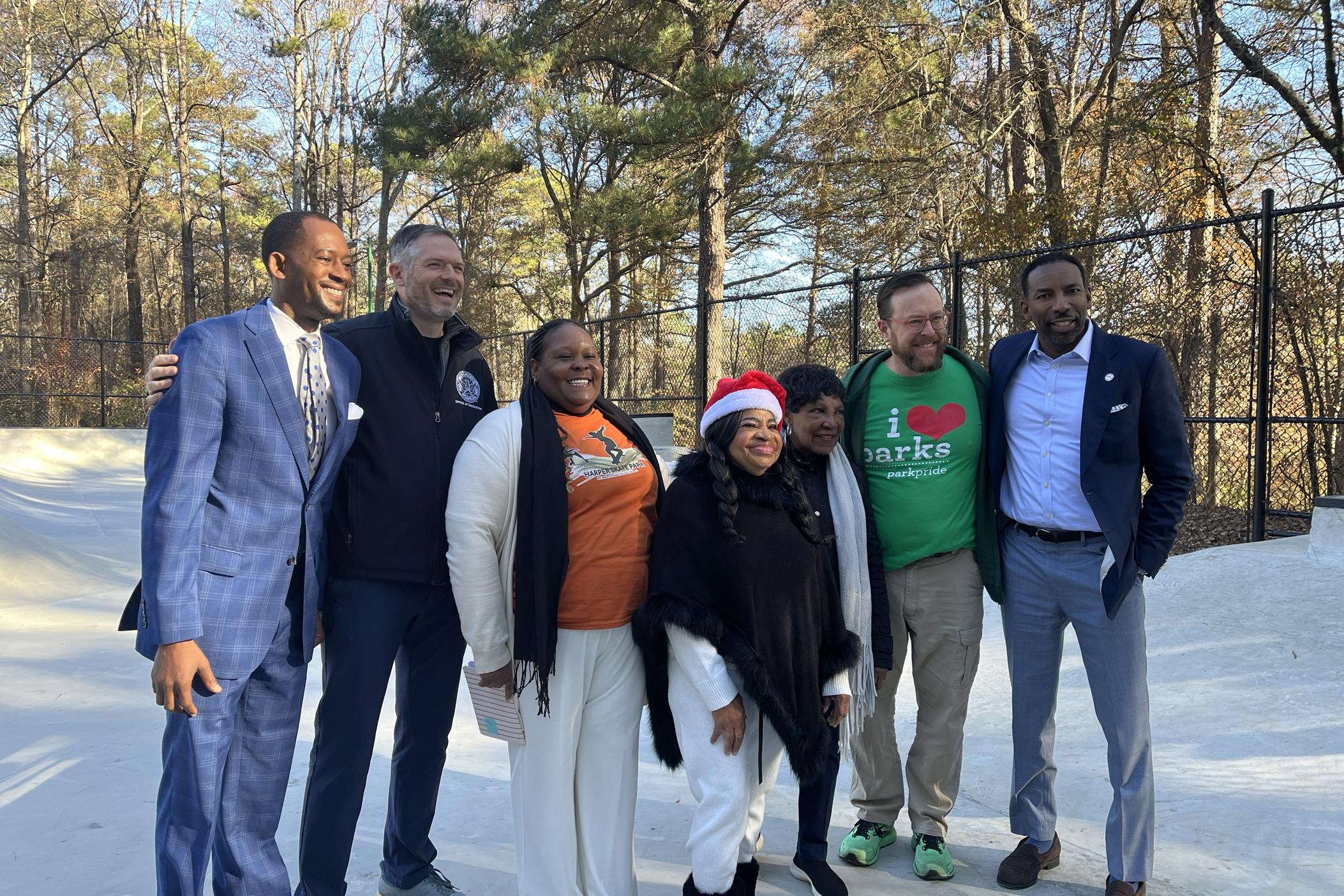 Joyce Smith wearing a santa hat joins city and community leaders for a picture after the opening remarks at Ruby Harper Skatepark on December 20, 2024.