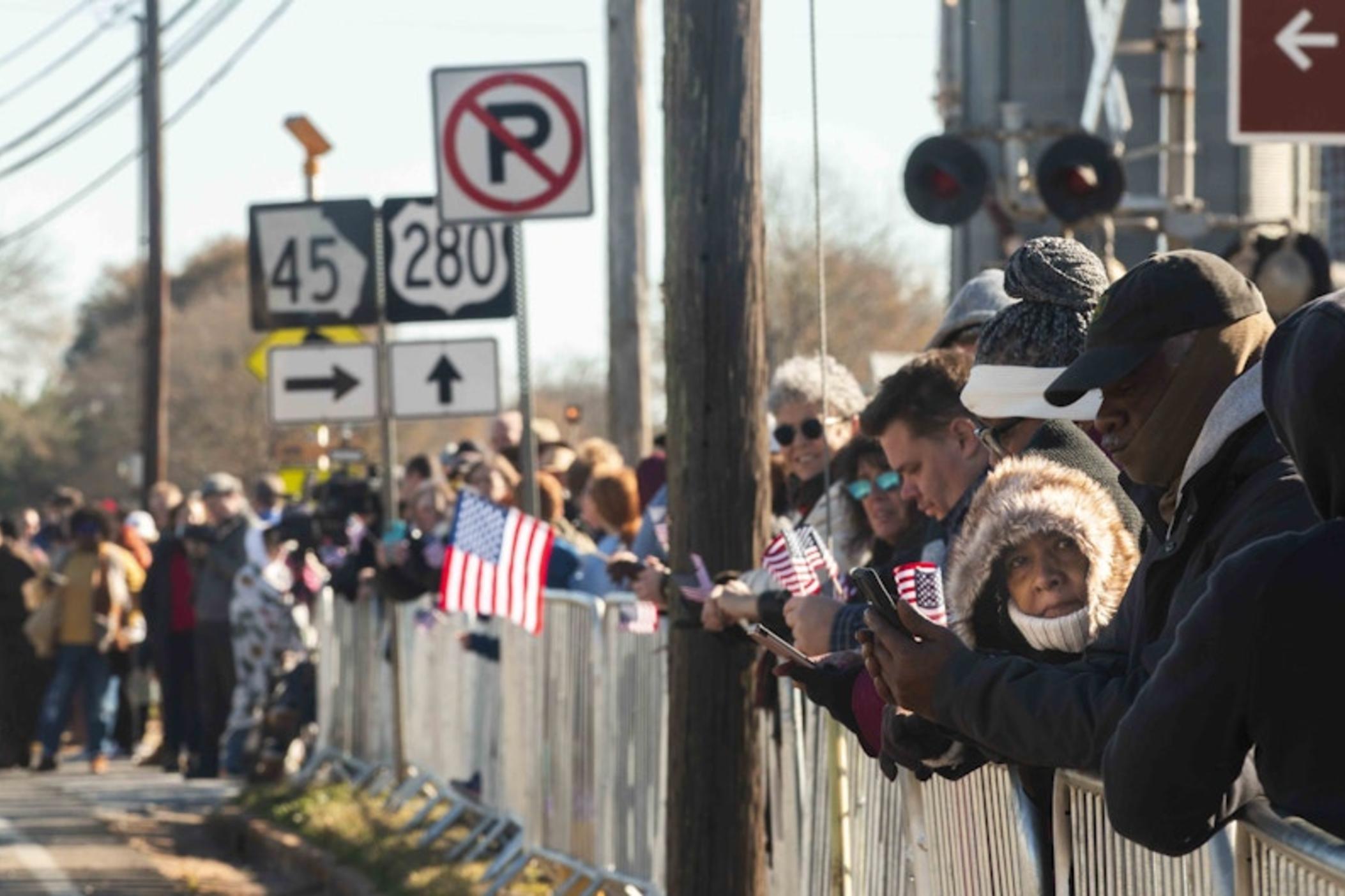 The crowd gathered to watch Jimmy Carter's funeral motorcade in downtown Plains just after it rolled through town. The first day of the six-day funeral schedule is a five-hour-plus journey from Plains to Atlanta ending with Carter lying in repose at the Carter Center. 