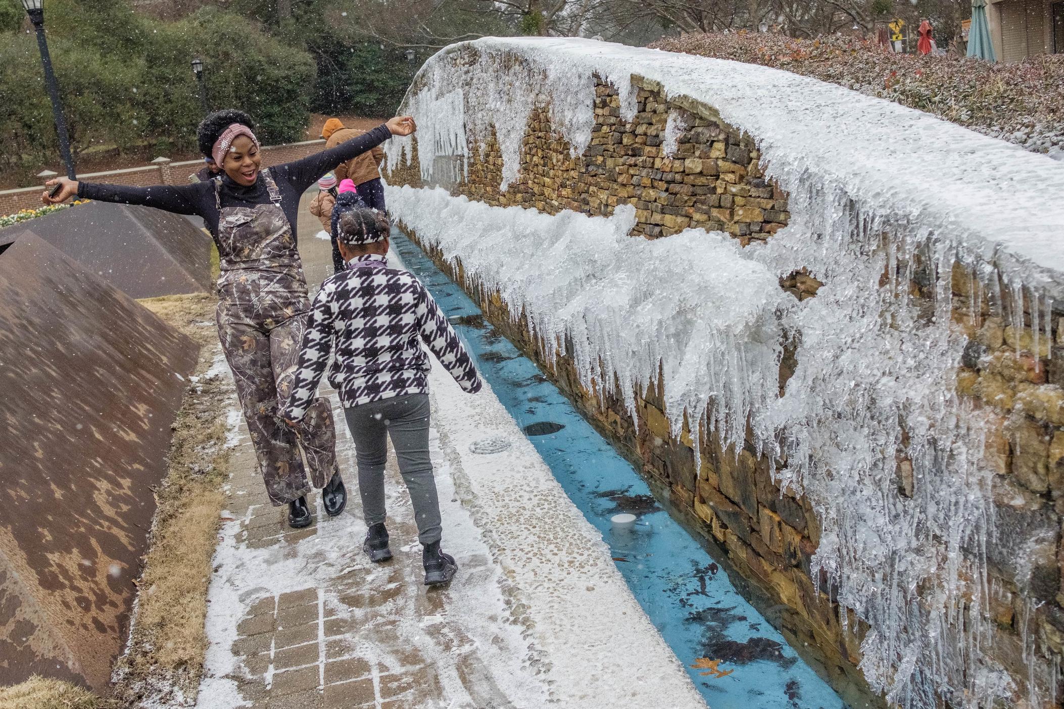 Earnestine Wilson and her daughter Anayla, 7, enjoy the early snowfall in Macon Tuesday, Anayla's first. "She's having a ball!" her mother said. Grant Blankenship/GPB News