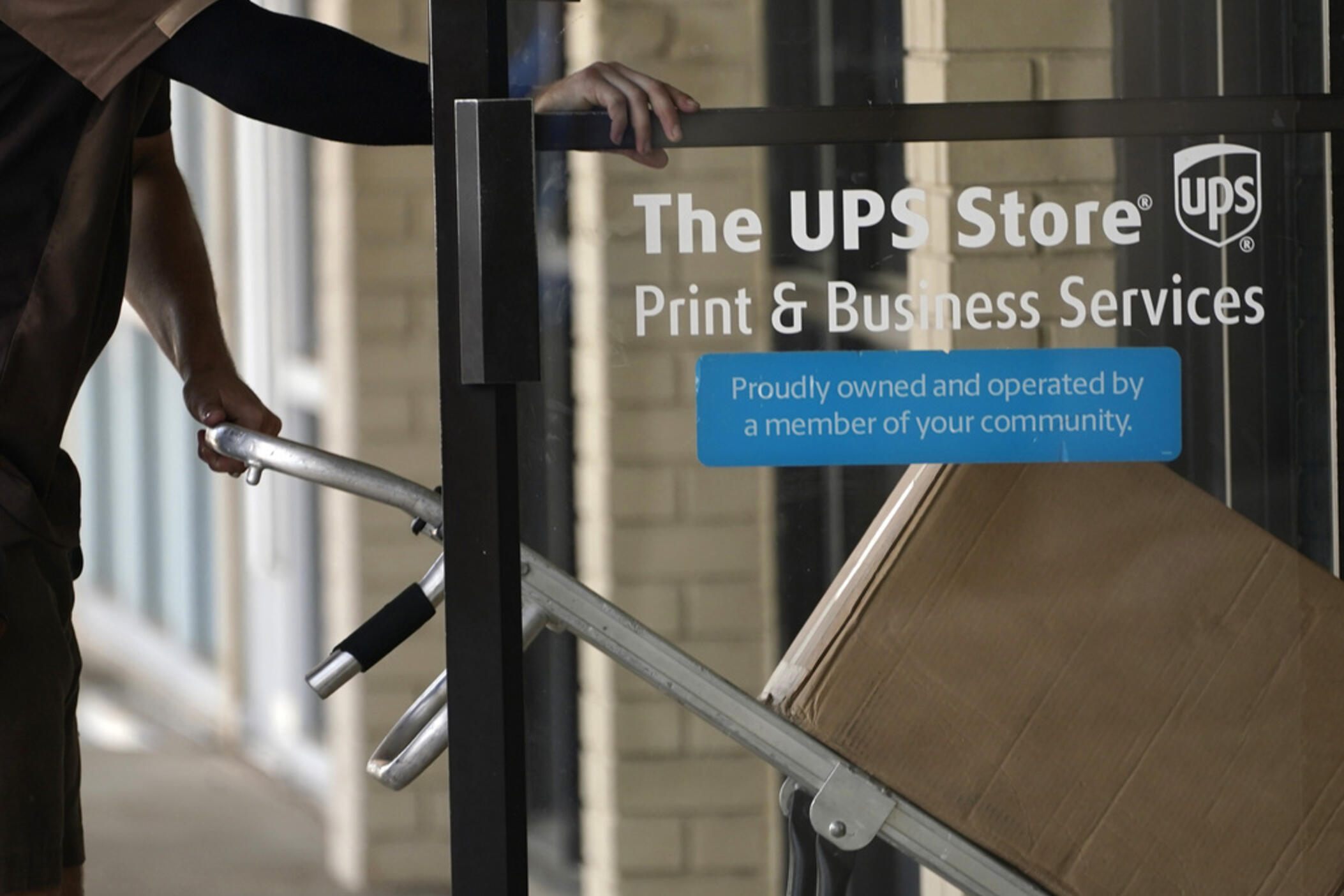 A UPS driver enters a United Parcel Service store with packages in Jackson, Miss., Monday, July 26, 2021.