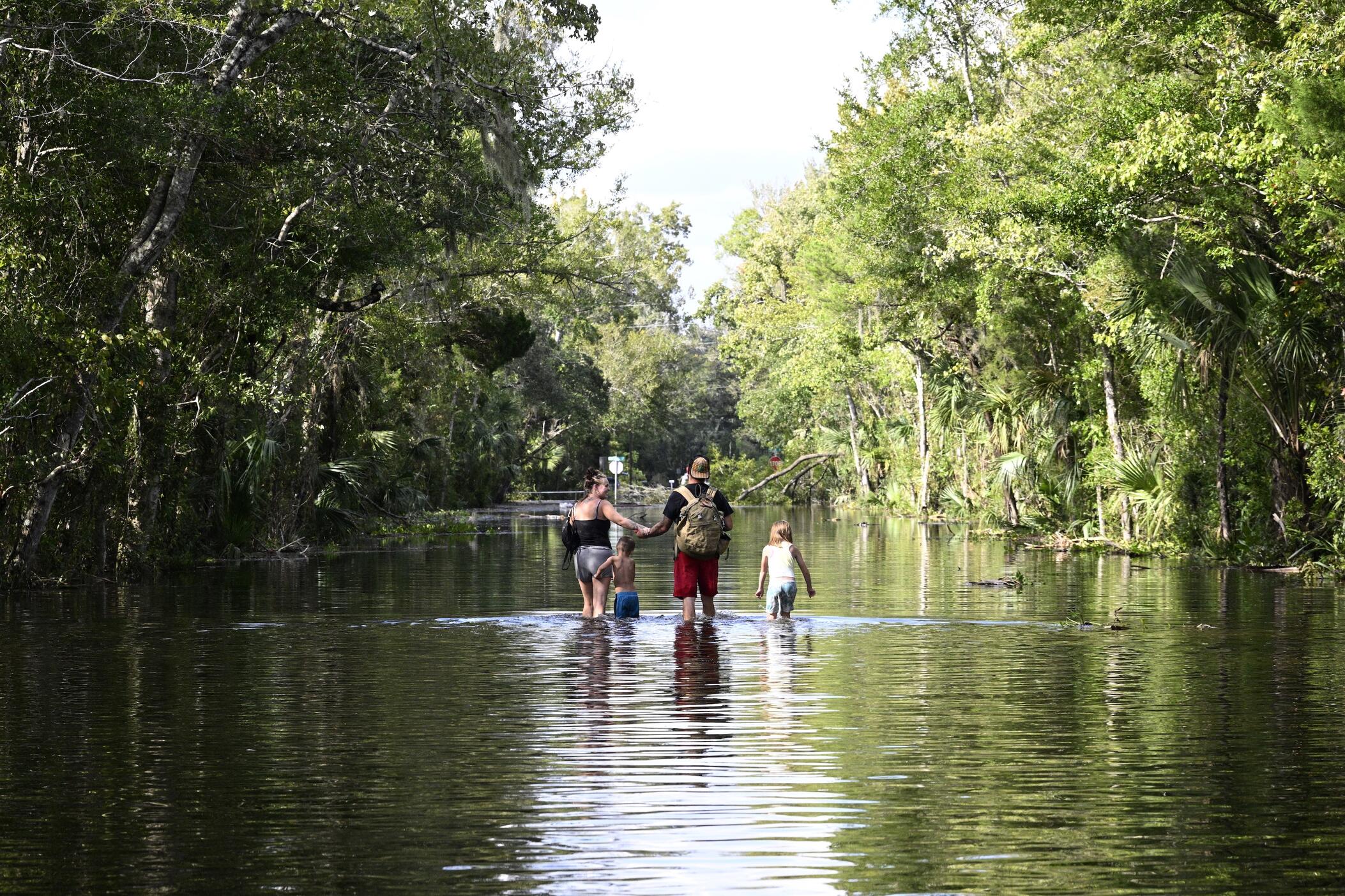  Dustin Holmes, second from right, holds hands with his girlfriend, Hailey Morgan, while returning to their flooded home with her children Aria Skye Hall, 7, right, and Kyle Ross, 4, in the aftermath of Hurricane Helene, Sept. 27, 2024, in Crystal River, Fla.