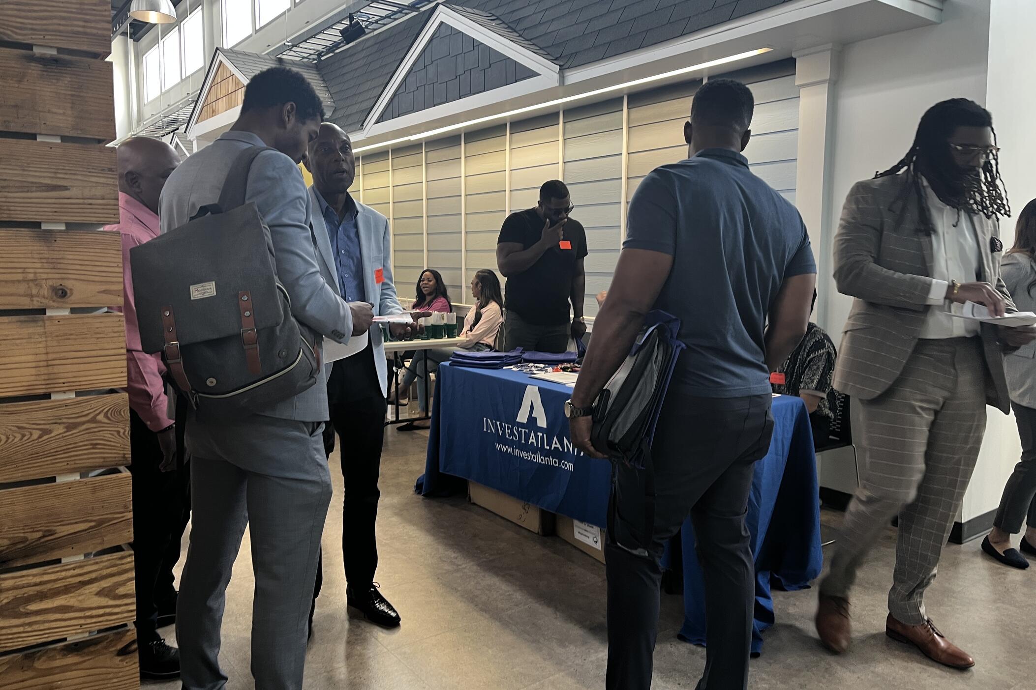 A group of conference attendees stand in front of an Invest Atlanta informational table. 